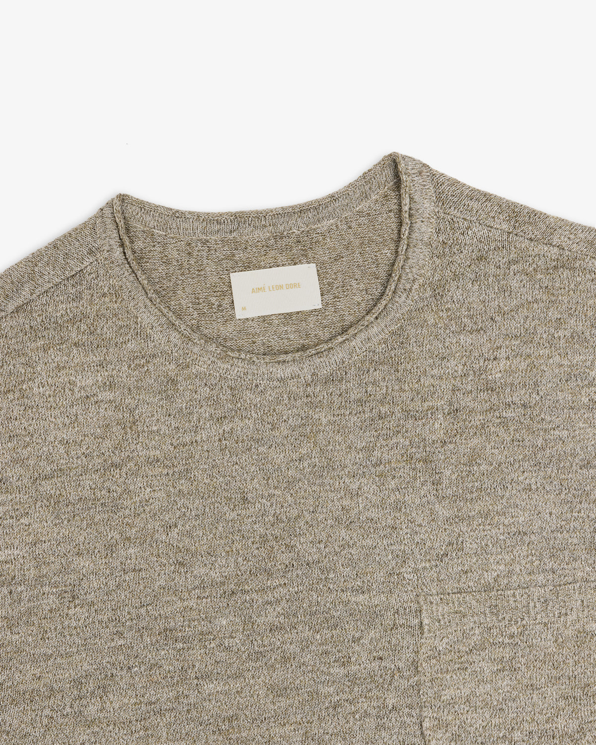 Beige Long-Sleeve Knit Pocket Tee with a visible white label in the collar, laid flat on a white background.