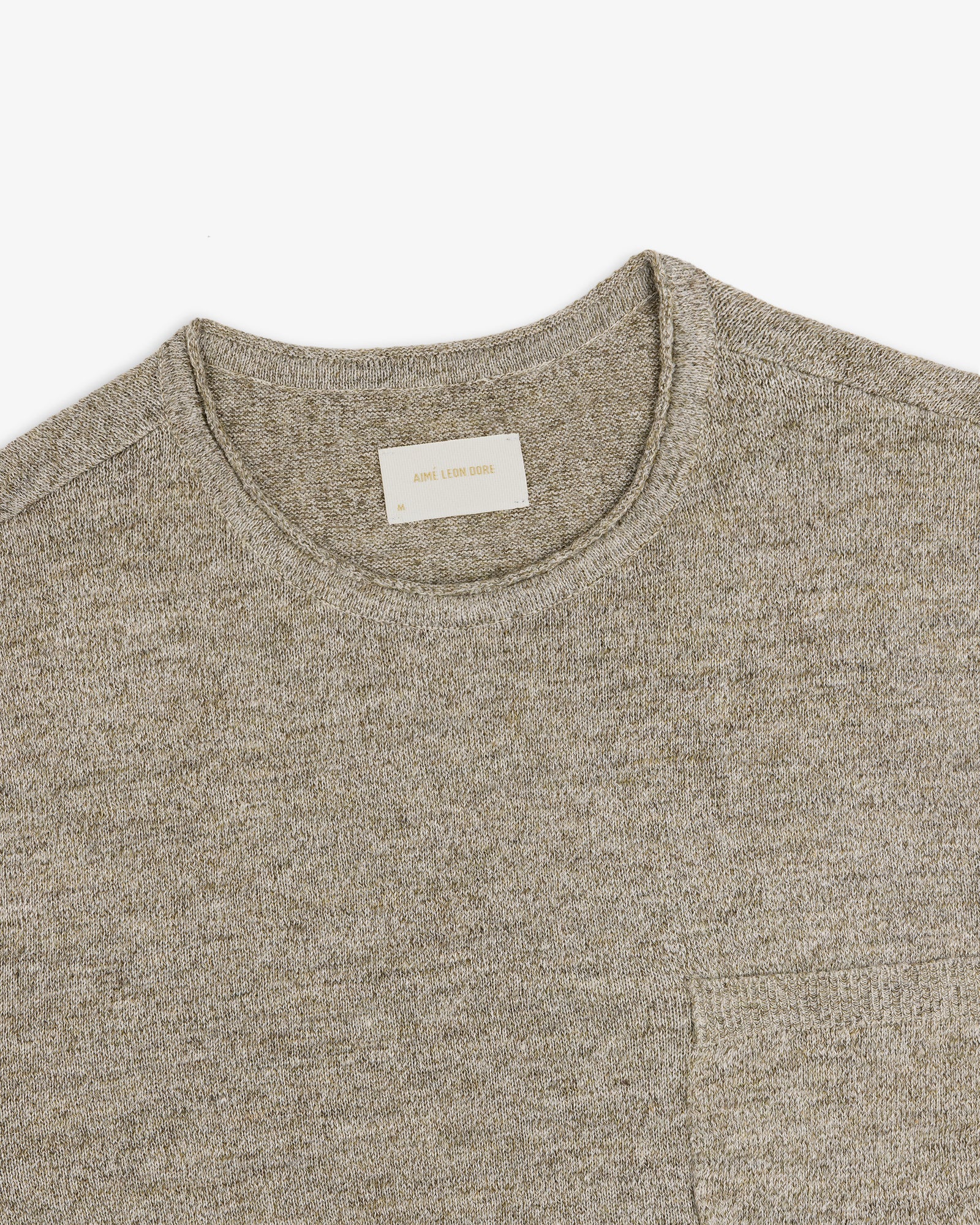 Beige Long-Sleeve Knit Pocket Tee with a visible white label in the collar, laid flat on a white background.