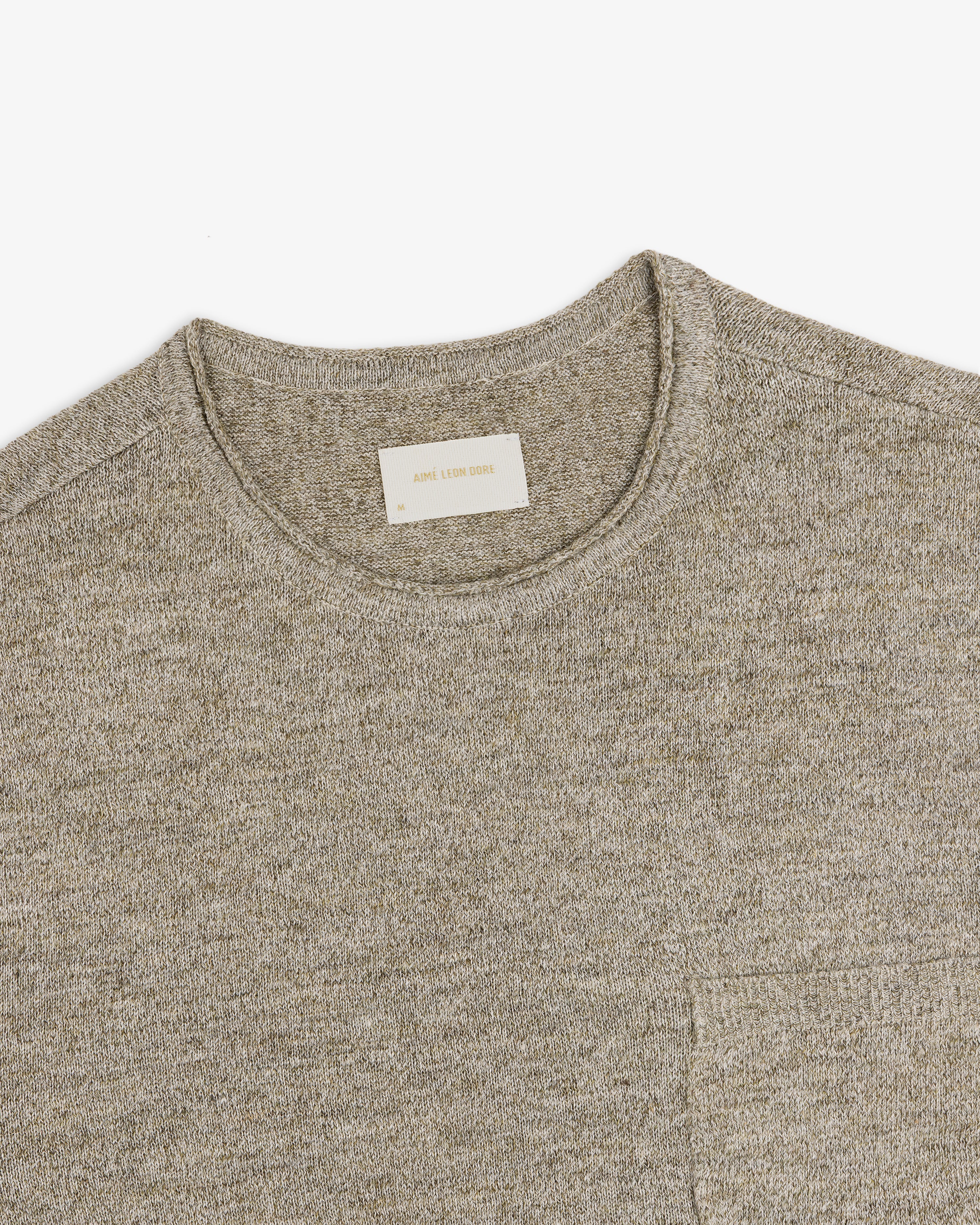 Beige Long-Sleeve Knit Pocket Tee with a visible white label in the collar, laid flat on a white background.