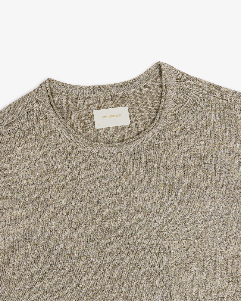 Beige Long-Sleeve Knit Pocket Tee with a visible white label in the collar, laid flat on a white background.