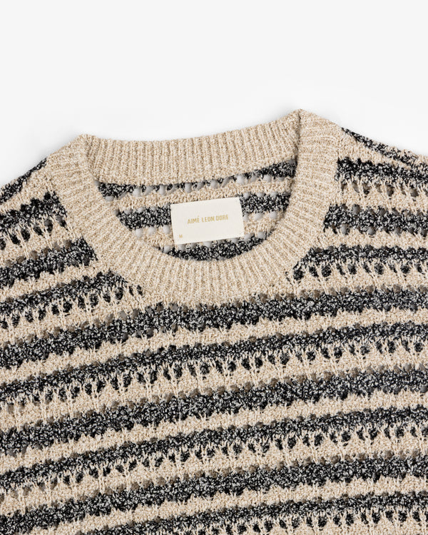 Close-up of a Bouclé Open Knit Crewneck Sweater in beige and black stripes on a white background.