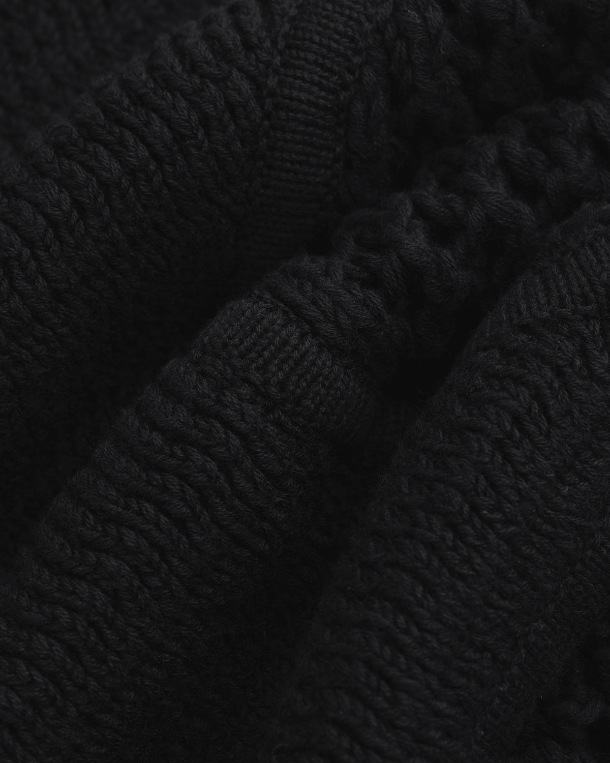 Close-up of Knit Court Short's black knitted fabric with textured patterns and soft, wavy folds.