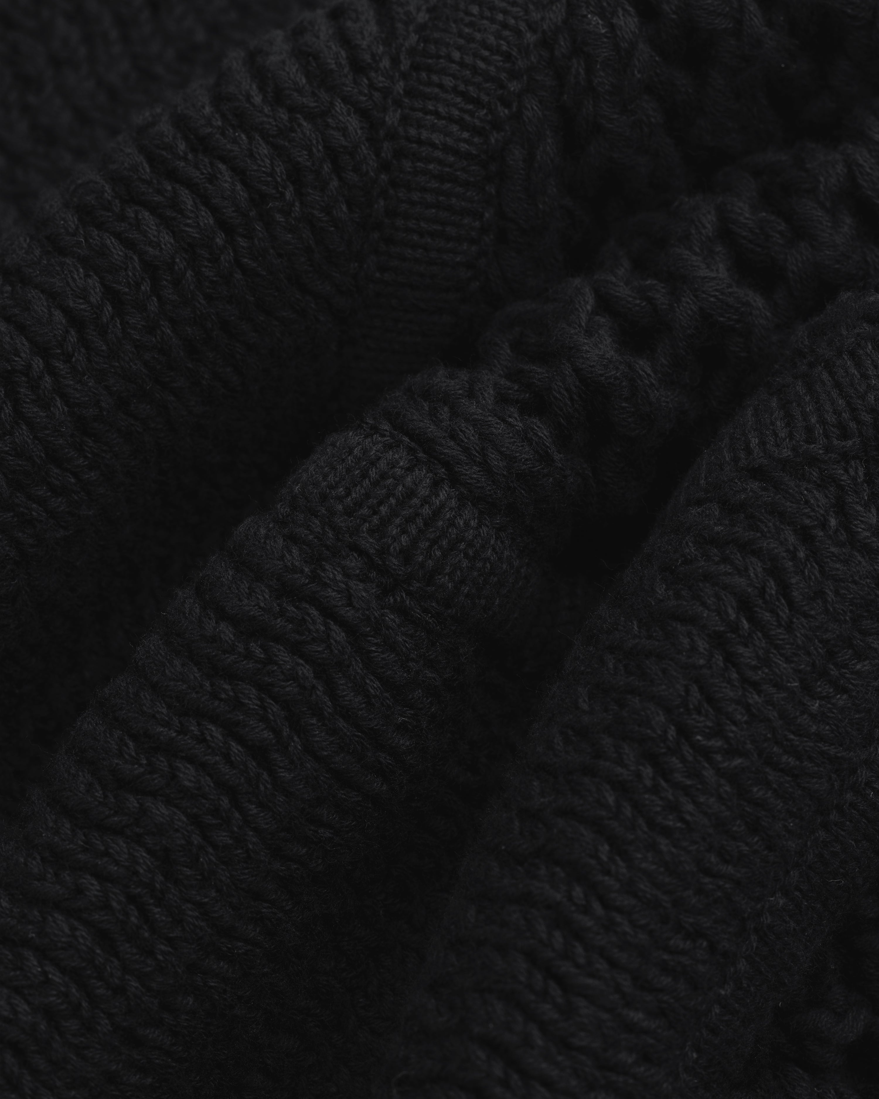 Close-up of Knit Court Short's black knitted fabric with textured patterns and soft, wavy folds.