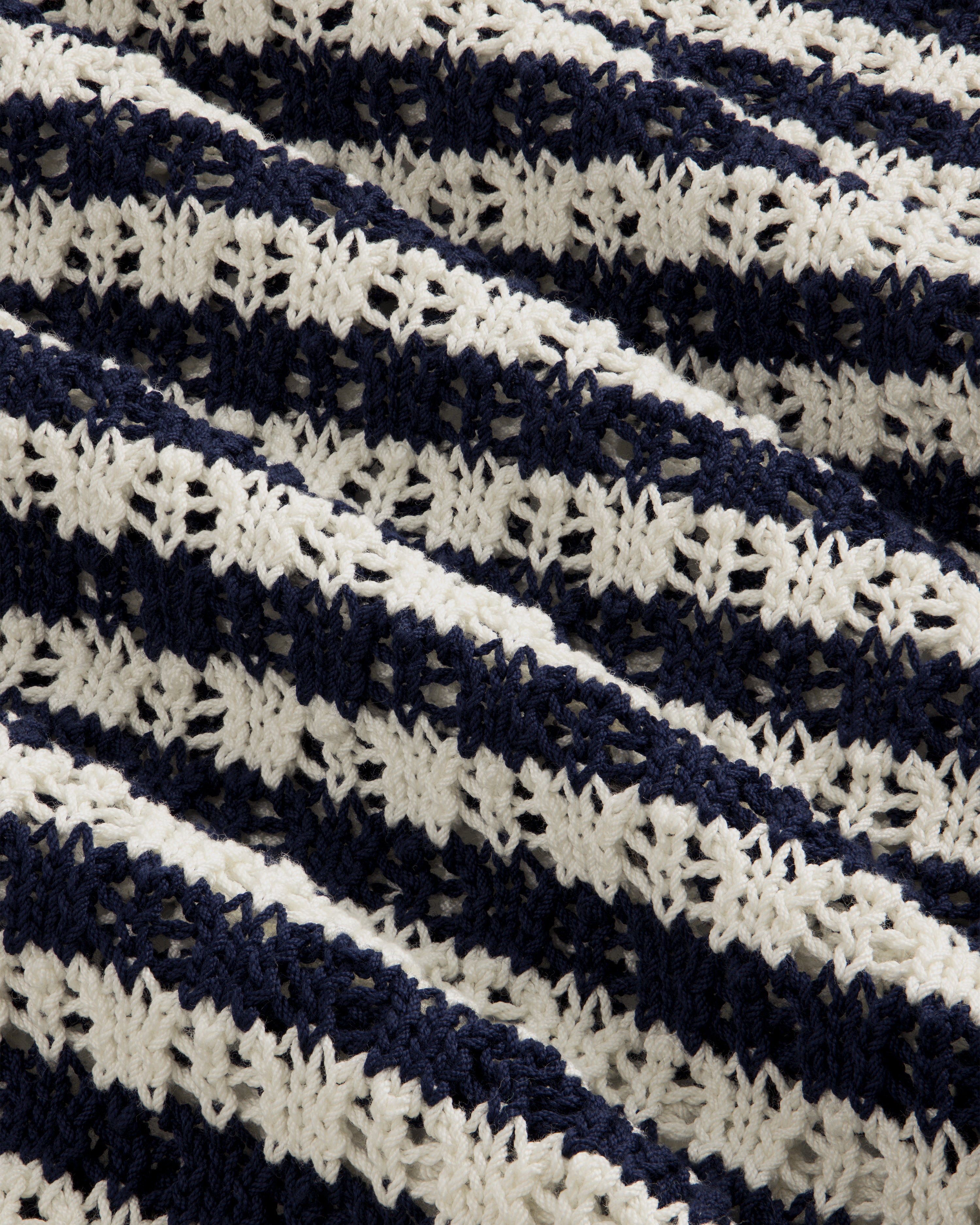 Close-up of the Skáfos Sweater’s knitted fabric with navy blue and white textured horizontal stripes.