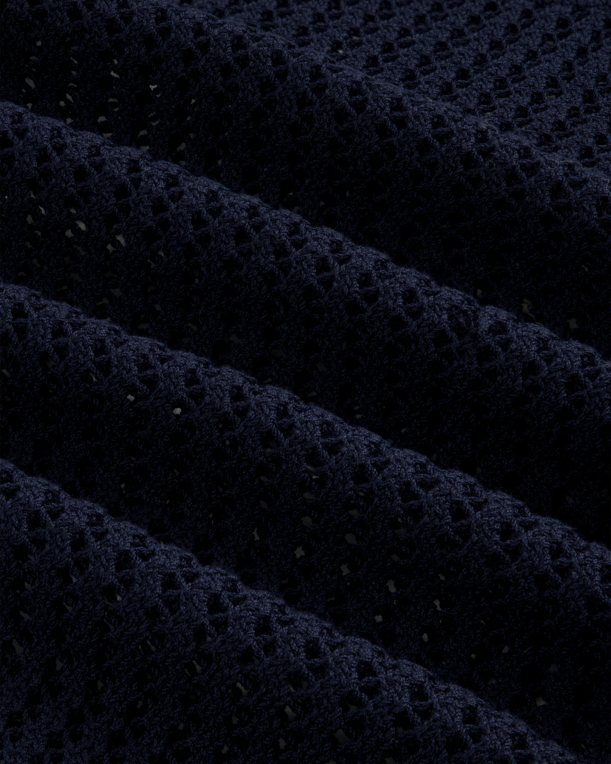 Close-up of the Cotton Eyelet Crewneck Sweater in dark blue, featuring textured waffle-knit and small perforations.
