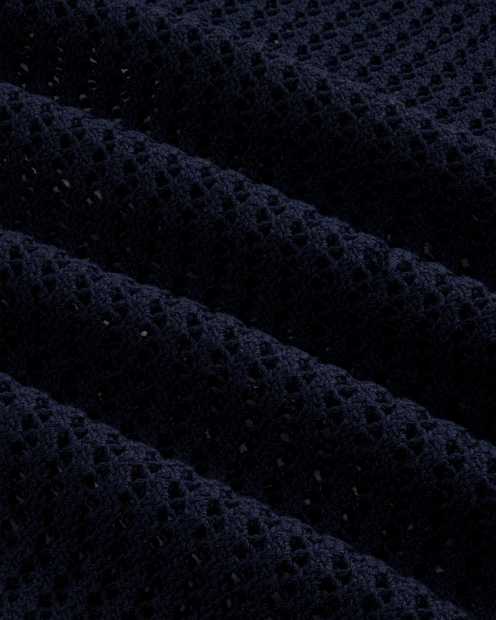 Close-up of the Cotton Eyelet Crewneck Sweater in dark blue, featuring textured waffle-knit and small perforations.