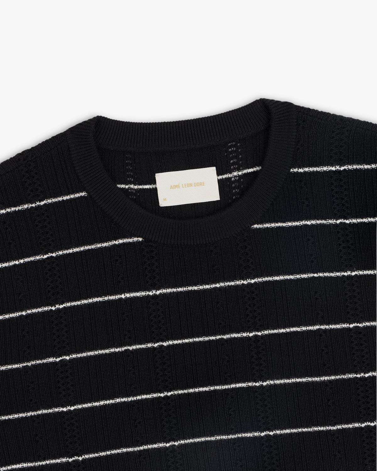 Merino Wool Eyelet Tee in black with white horizontal stripes and a visible white collar label.