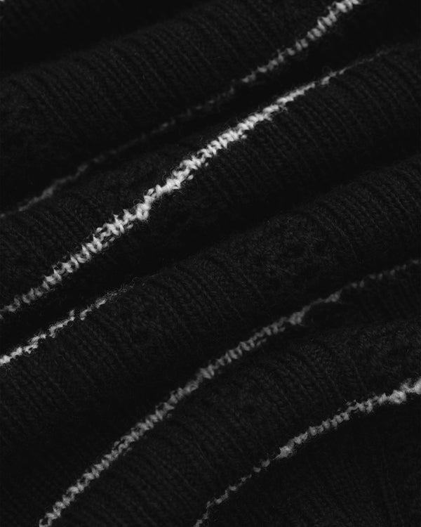Close-up of Merino Wool Eyelet Tee in black with thin white diagonal stripes on ribbed knit fabric.