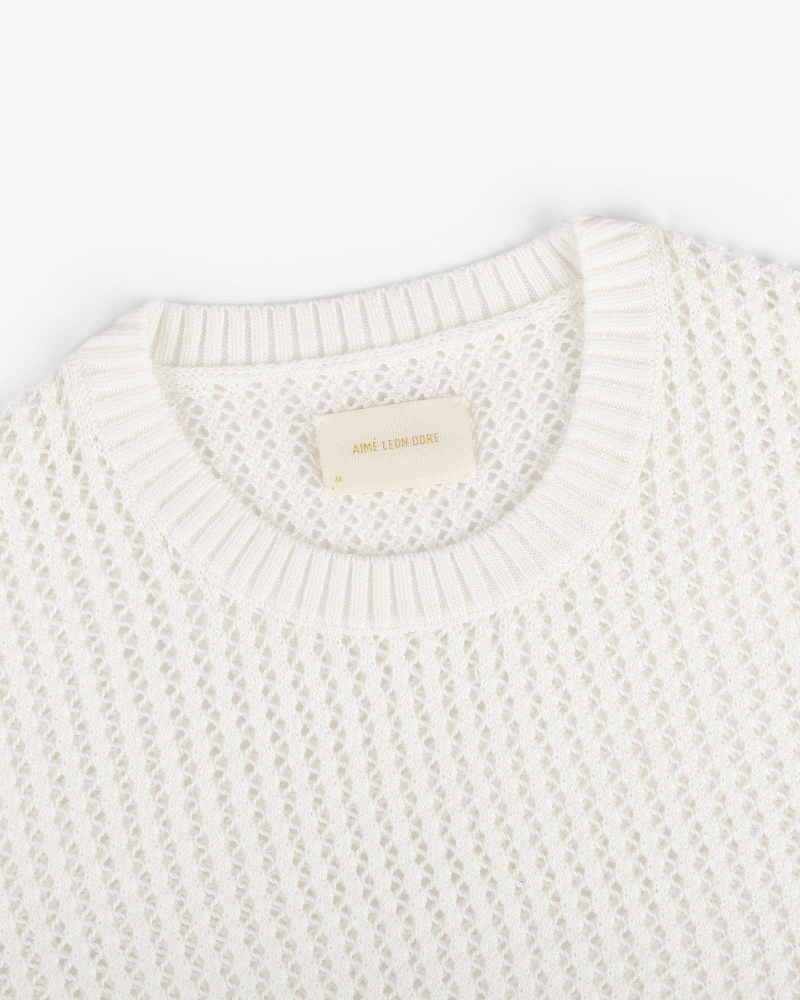 The Fassianos "Rendez-Vous" Crewneck Sweater is a white knit with a textured pattern and beige neckline label.