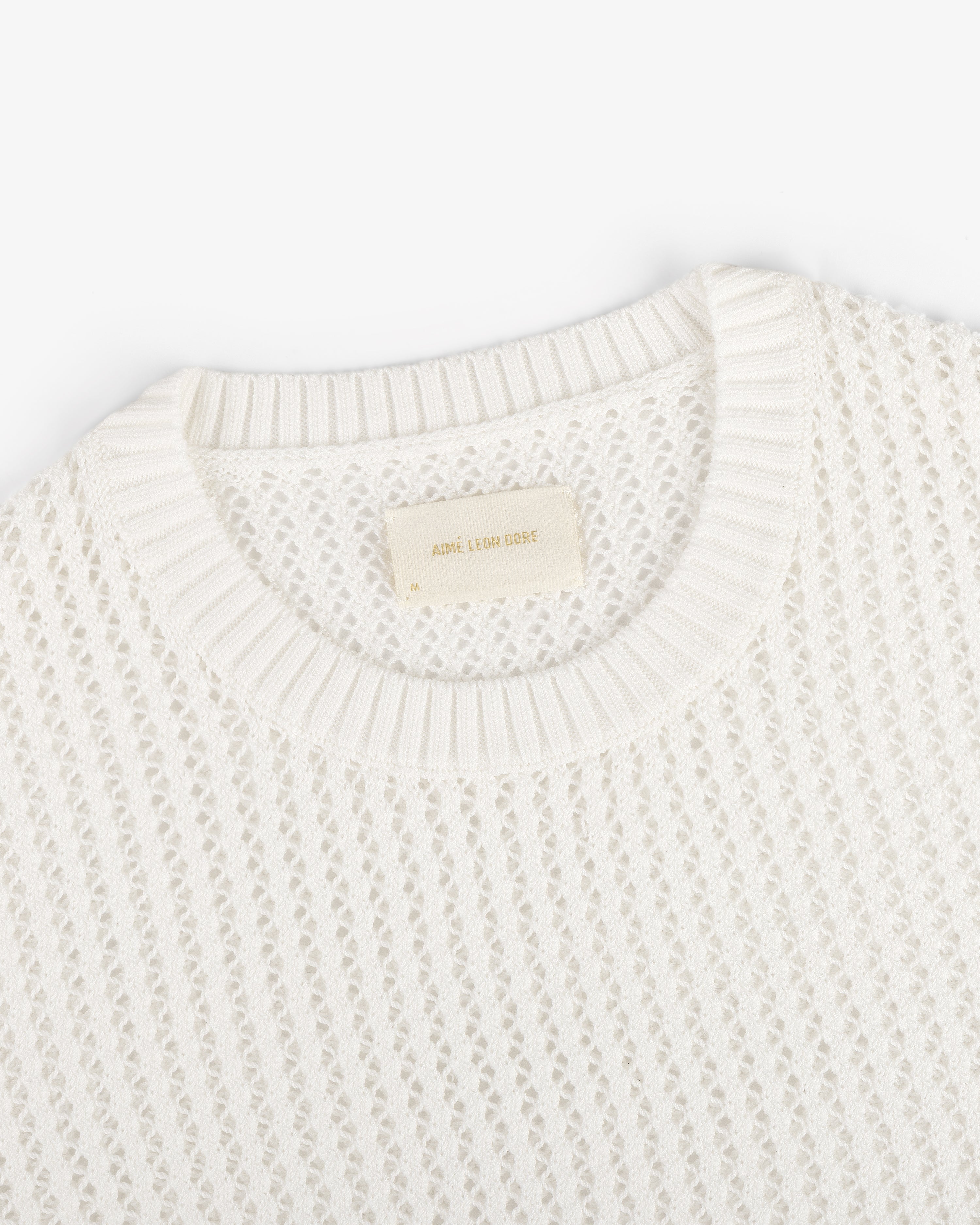The Fassianos "Rendez-Vous" Crewneck Sweater is a white knit with a textured pattern and beige neckline label.