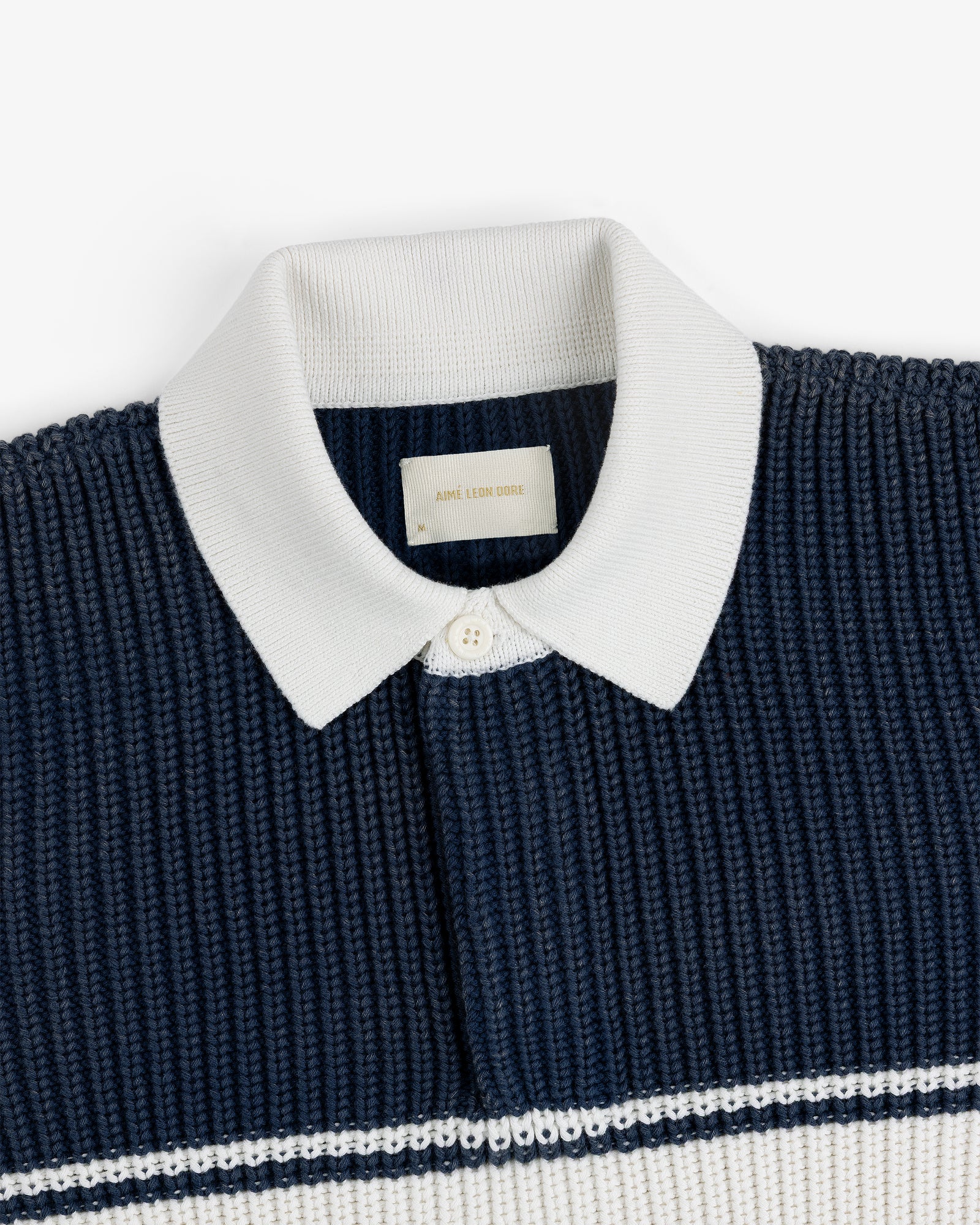 Striped Knit Rugby: Navy knit polo with white ribbed collar, button placket, and white stripes.
