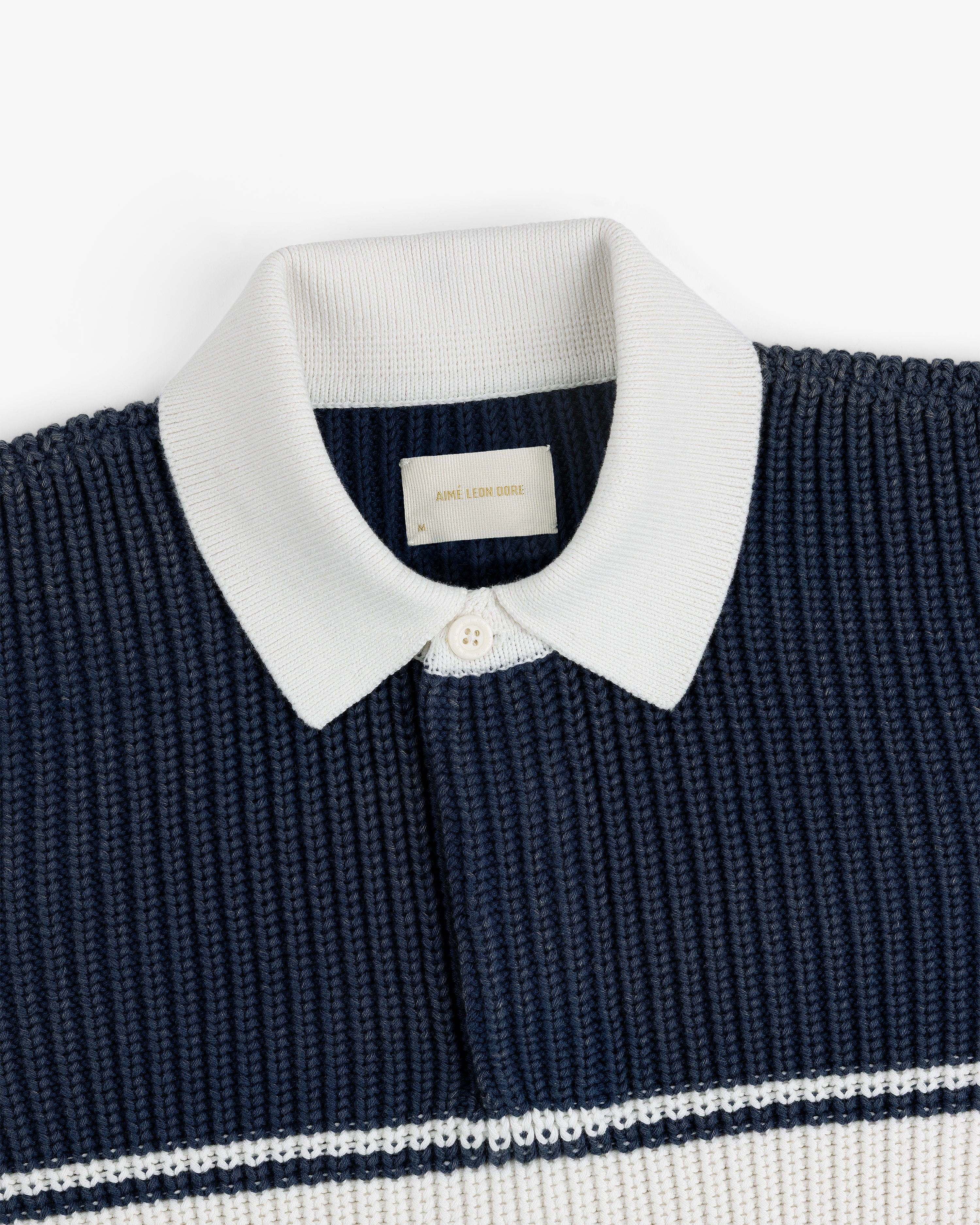 Striped Knit Rugby: Navy knit polo with white ribbed collar, button placket, and white stripes.