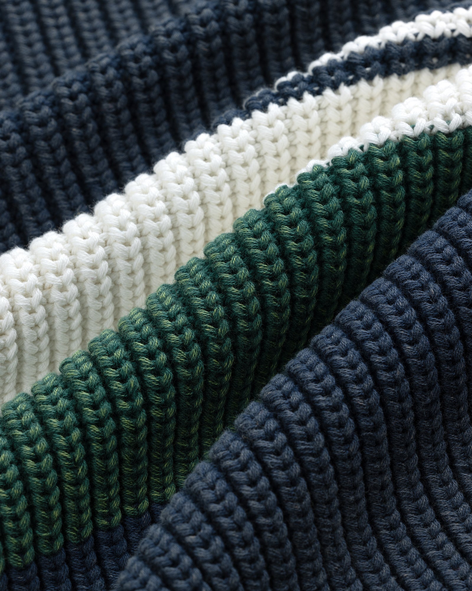 Close-up of Striped Knit Rugby fabric with dark blue, green, and white horizontal ribbed stripes.