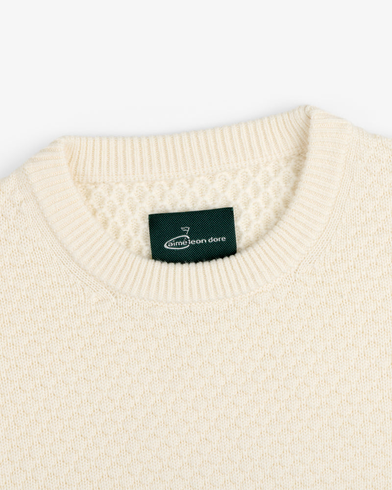 Cream-colored ALD Golf Clubhouse Sweater with textured knit, ribbed crew neckline, and green Aimé Leon Dore inside label.