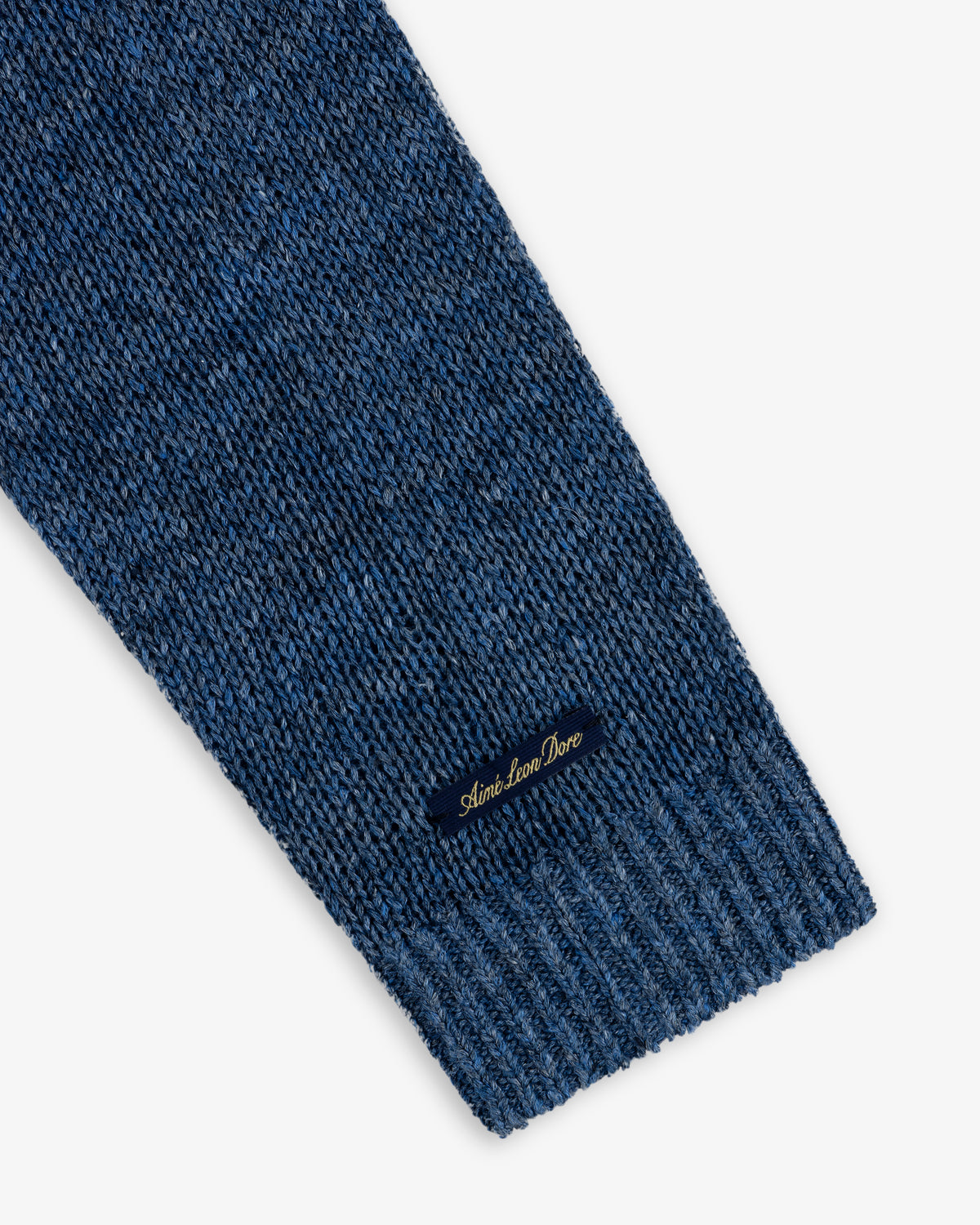 Close-up of a blue Linen Knit Crewneck Sweater sleeve with a small black label near the ribbed cuff.