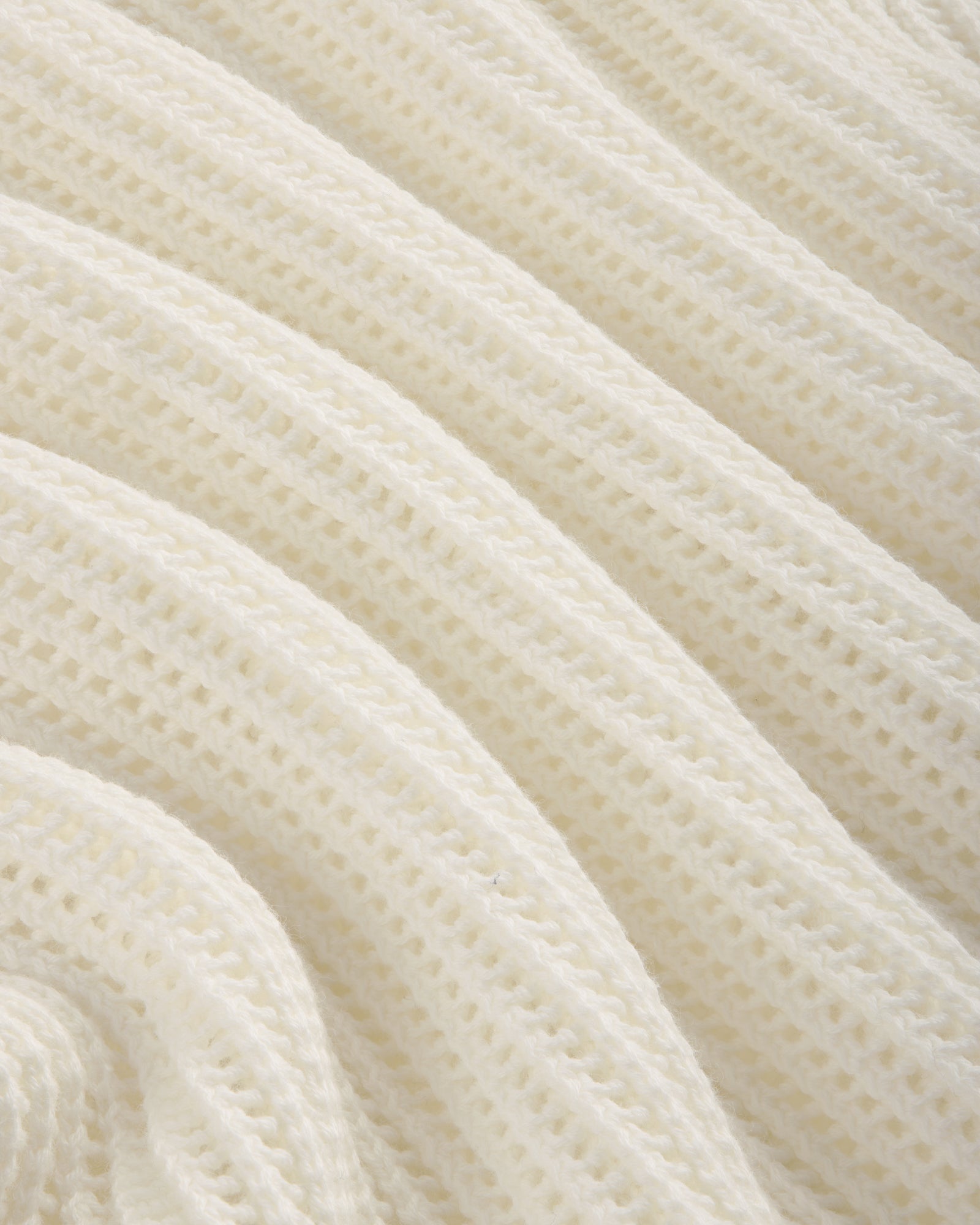 Close-up of the Mesh Knit Polo's soft, white ribbed fabric with a textured, wavy pattern.
