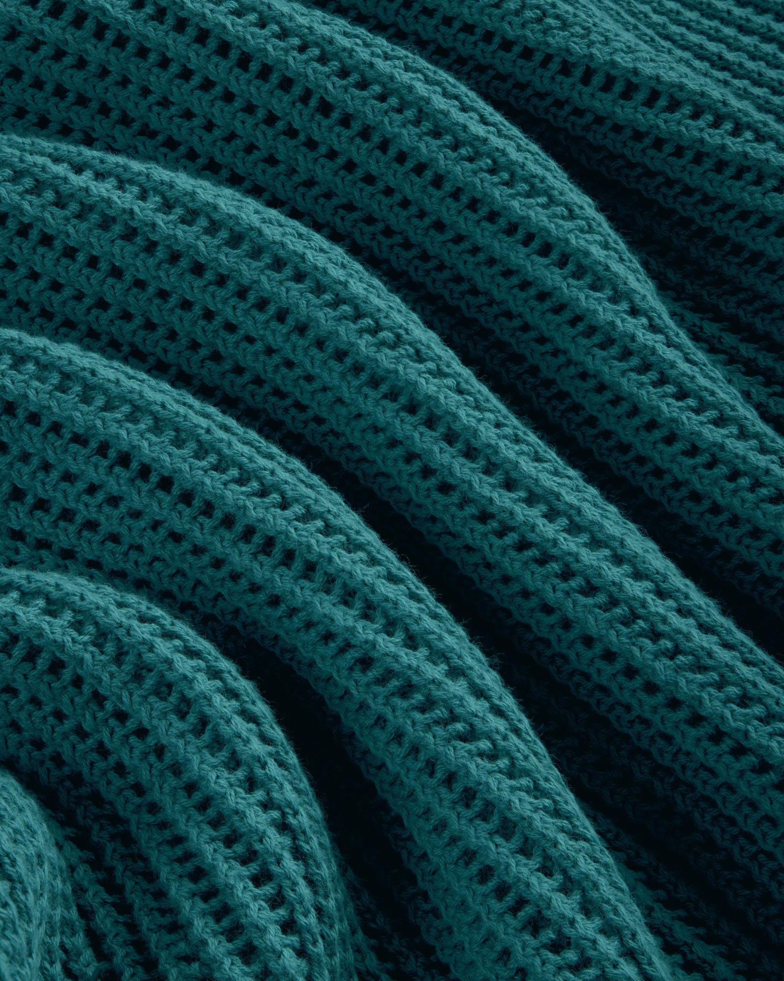 Close-up of Mesh Knit Polo in teal, featuring ribbed texture and wavy, repeating knit patterns.