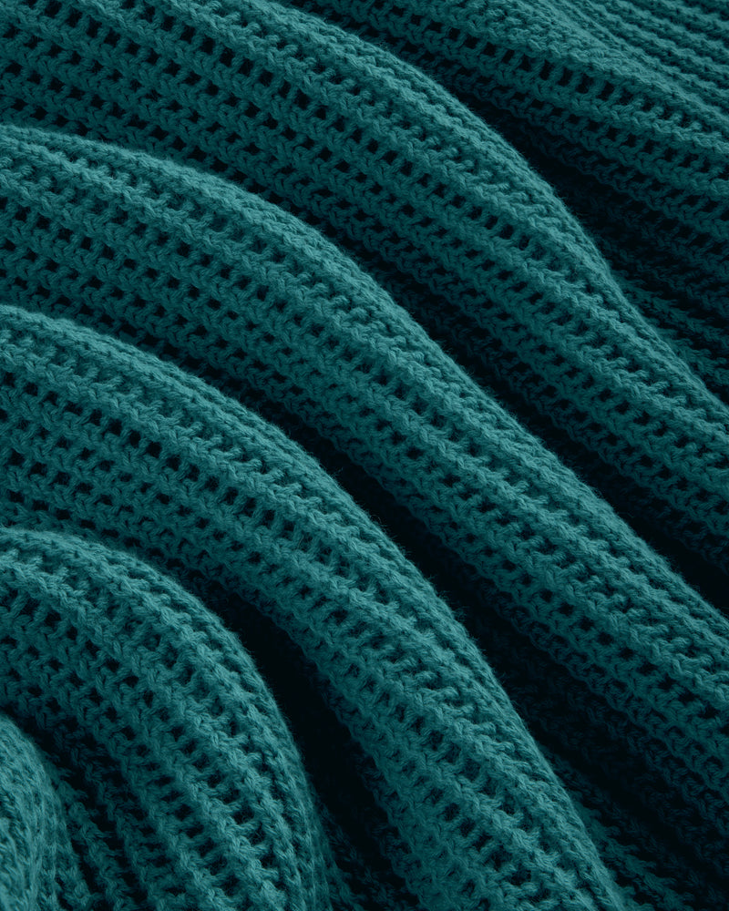 Close-up of Mesh Knit Polo in teal, featuring ribbed texture and wavy, repeating knit patterns.