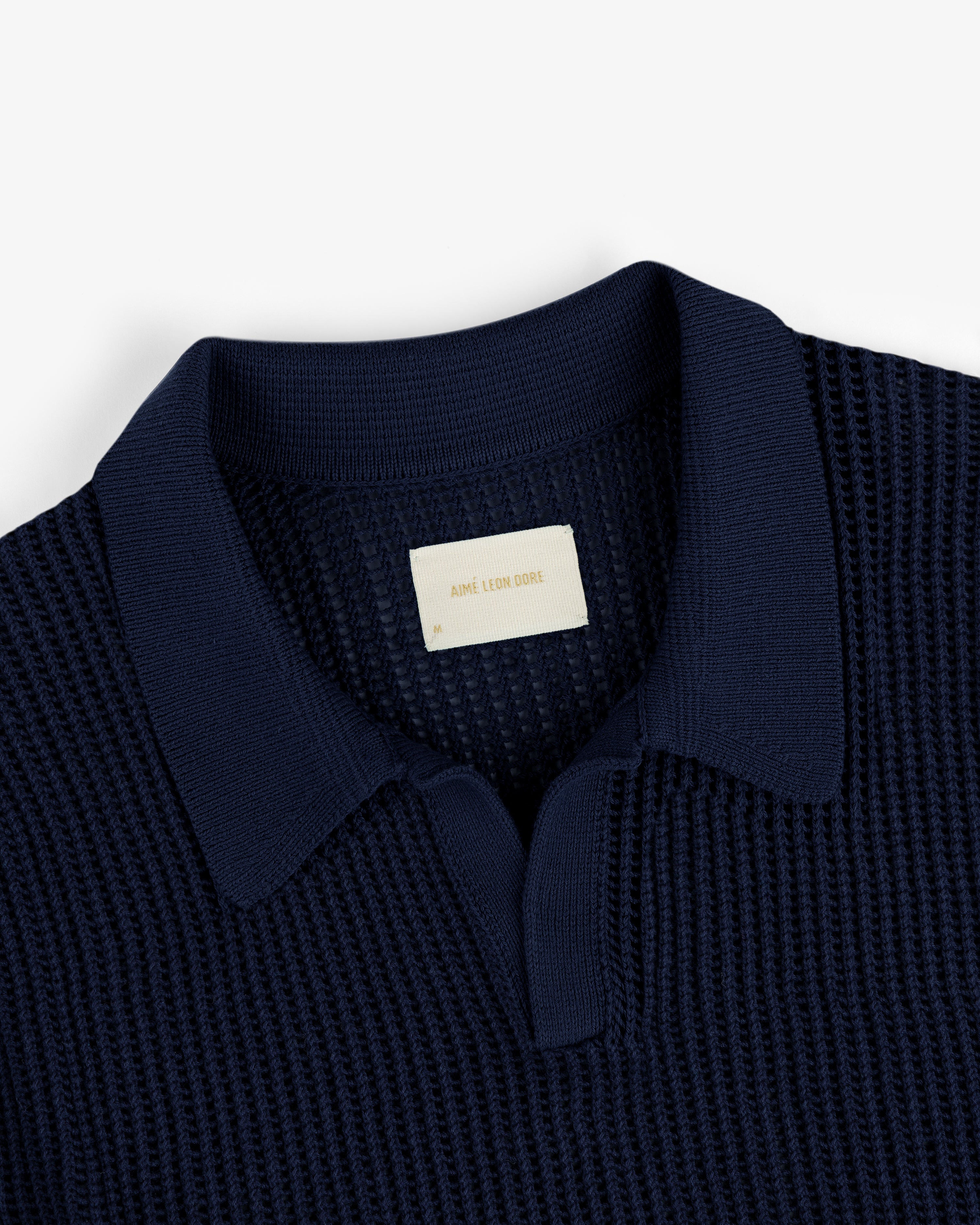 Navy blue Mesh Knit Polo featuring a textured design, spread collar, and visible Aimé Leon Dore label at the neckline.