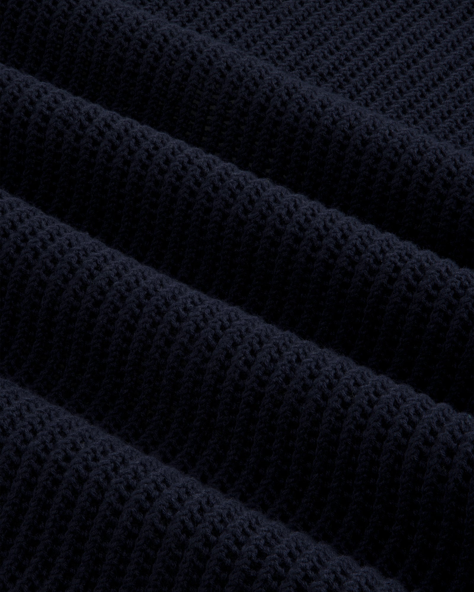 Close-up of Mesh Knit Polo’s dark navy ribbed fabric with a textured, repeating diagonal pattern.
