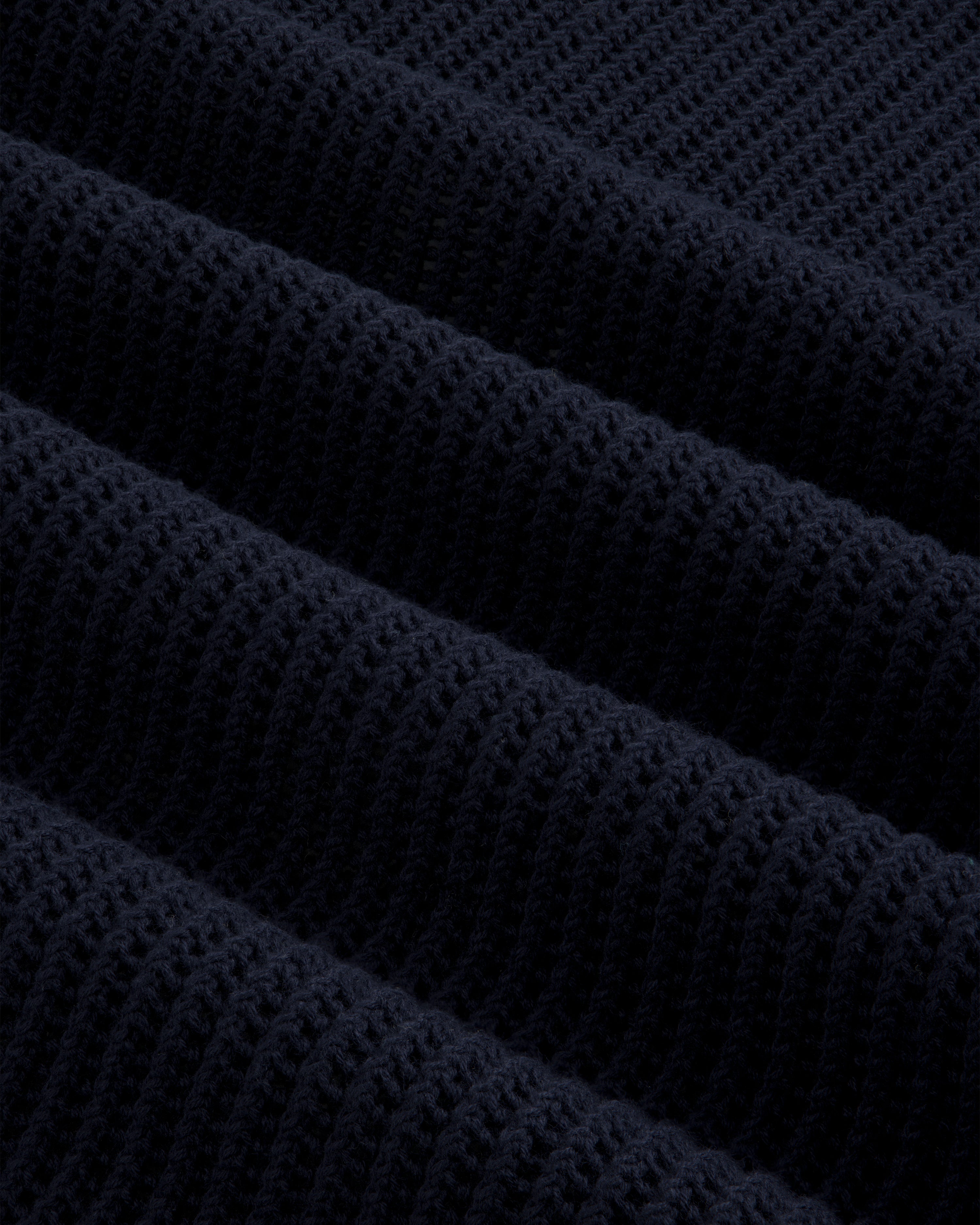 Close-up of Mesh Knit Polo’s dark navy ribbed fabric with a textured, repeating diagonal pattern.