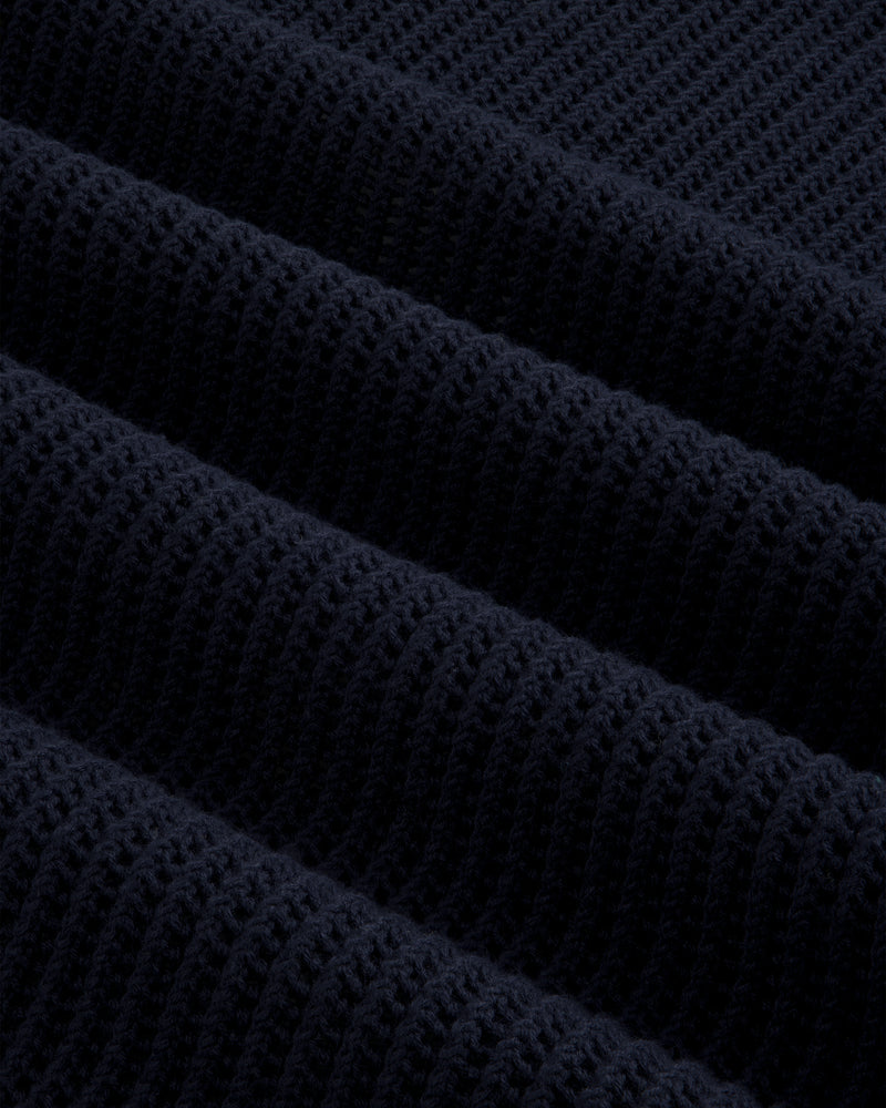 Close-up of Mesh Knit Polo’s dark navy ribbed fabric with a textured, repeating diagonal pattern.