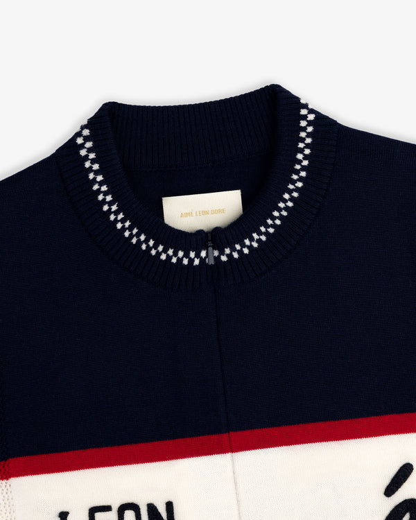 Navy Merino Wool Cycling Jersey with white and red stripes, ribbed collar, and Aimé Leon Dore label at the neck.