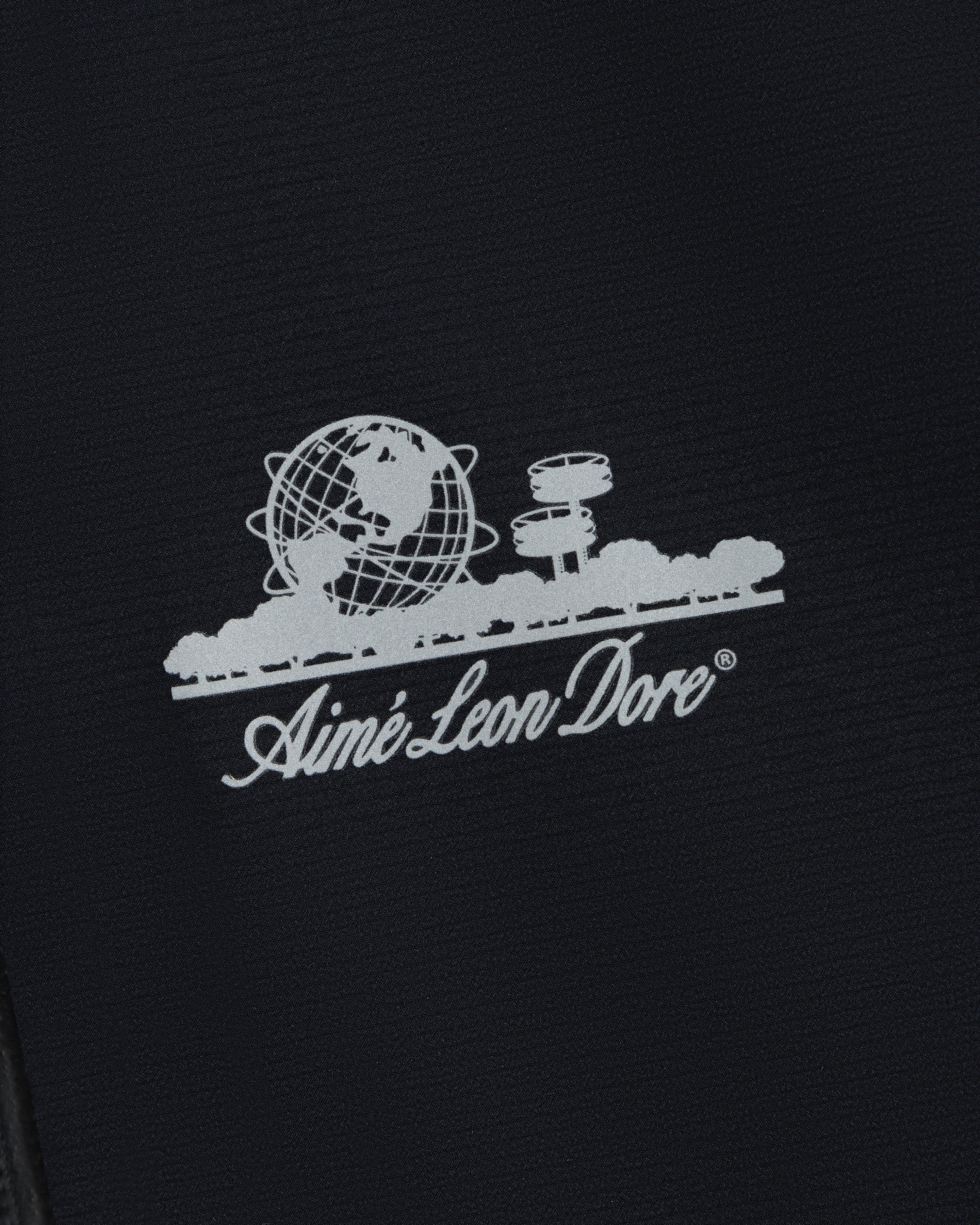 White Aimé Leon Dore logo with globe, trees, and observatory on the Lightweight GORE-TEX Shell Jacket.