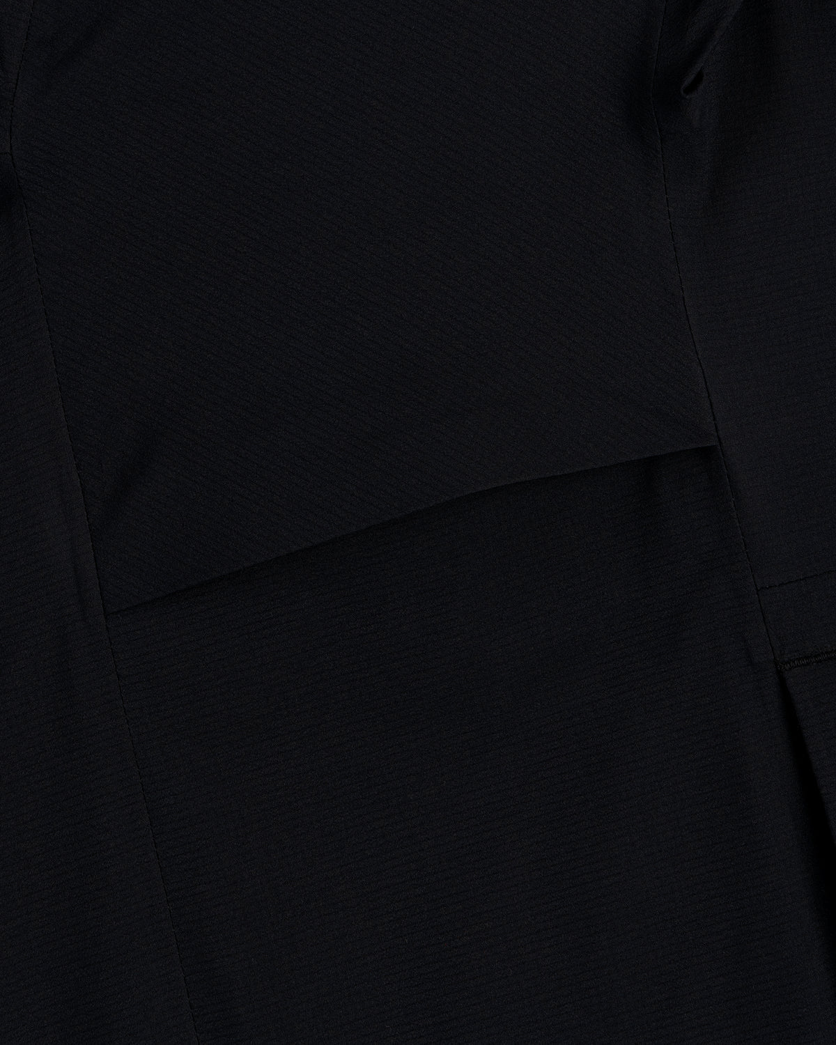 Close-up of black fabric with a seam on the Lightweight GORE-TEX Shell Jacket showing its subtle texture.