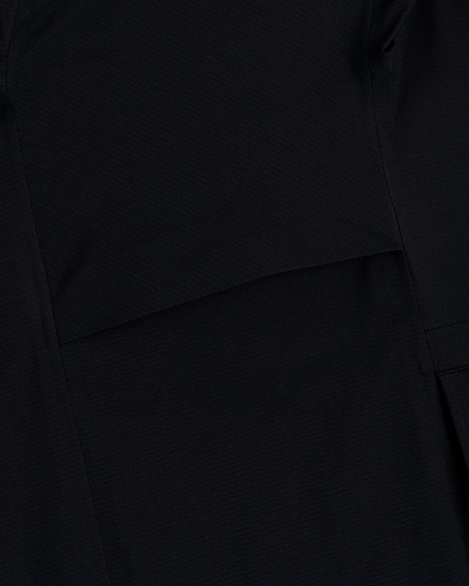 Close-up of black fabric with a seam on the Lightweight GORE-TEX Shell Jacket showing its subtle texture.