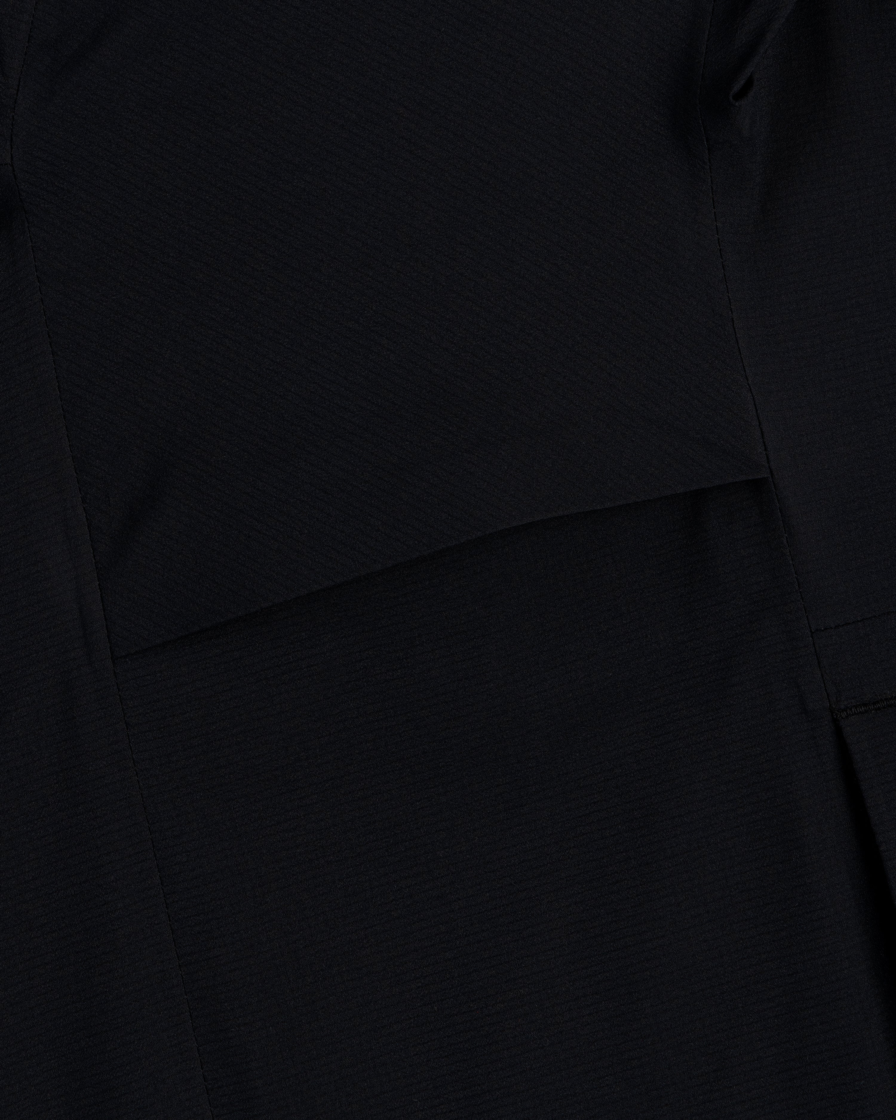 Close-up of black fabric with a seam on the Lightweight GORE-TEX Shell Jacket showing its subtle texture.