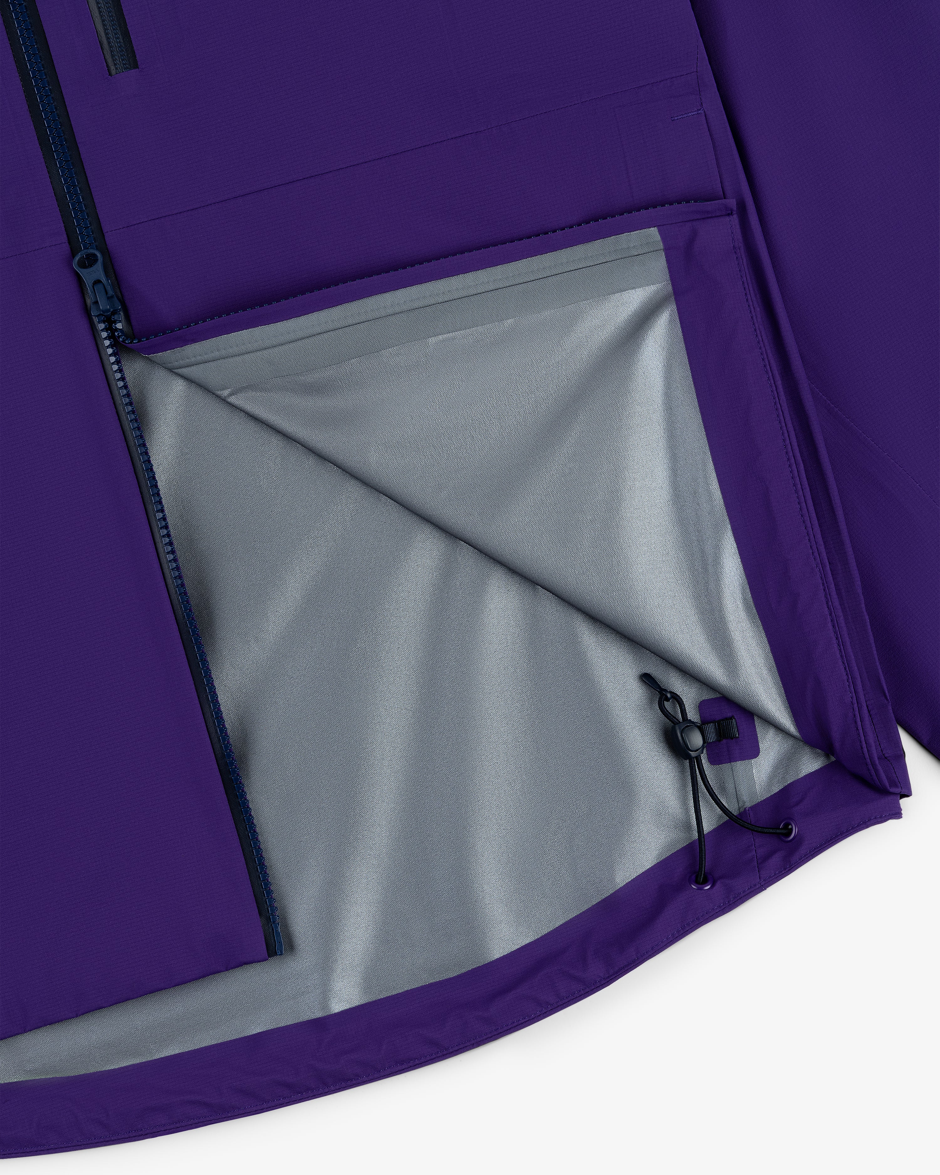 Close-up of the Lightweight GORE-TEX Shell Jacket in purple with a gray lining and partially unzipped side pocket.