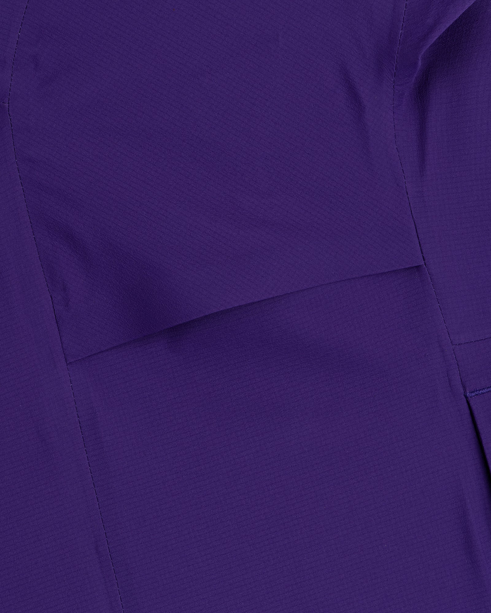 Close-up of purple GORE-TEX Shell Jacket fabric showing visible stitching and subtle texture.
