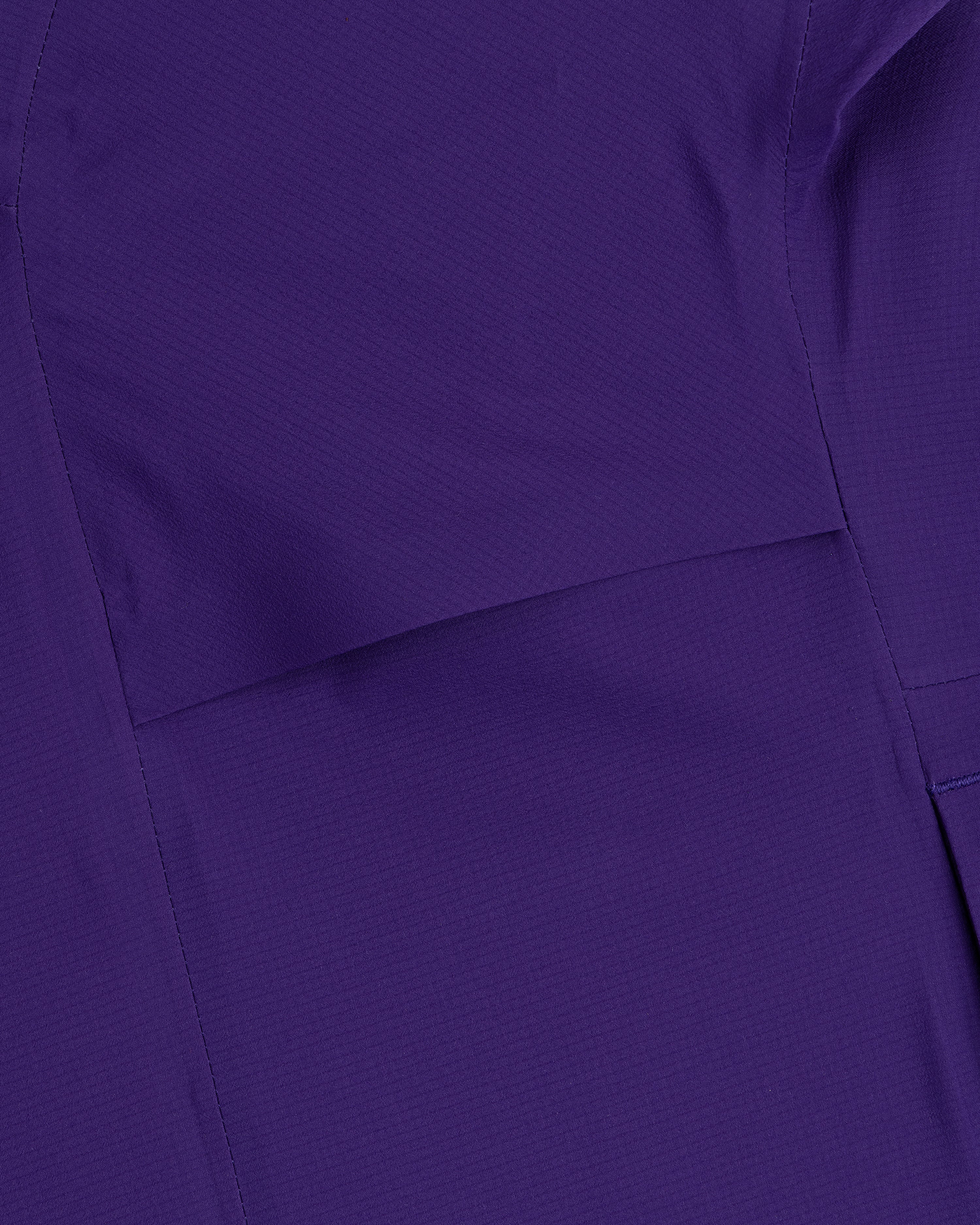 Close-up of purple GORE-TEX Shell Jacket fabric showing visible stitching and subtle texture.