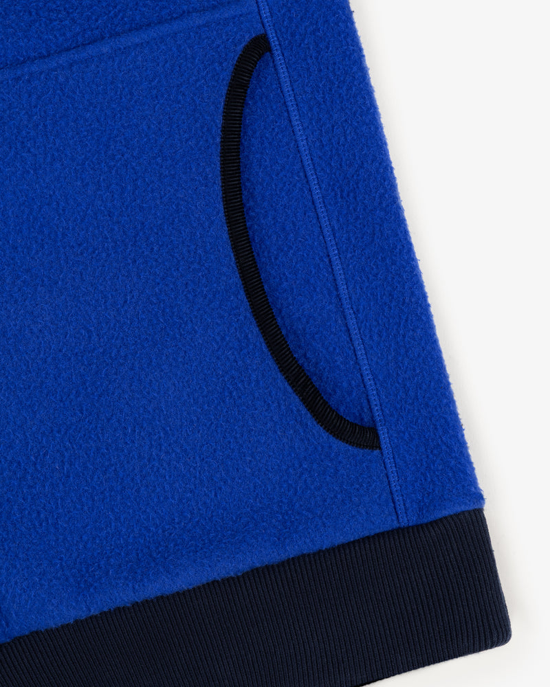 Close-up of the Casentino Crest Half-Zip Pullover in blue with a black-trimmed pocket and ribbed hem.