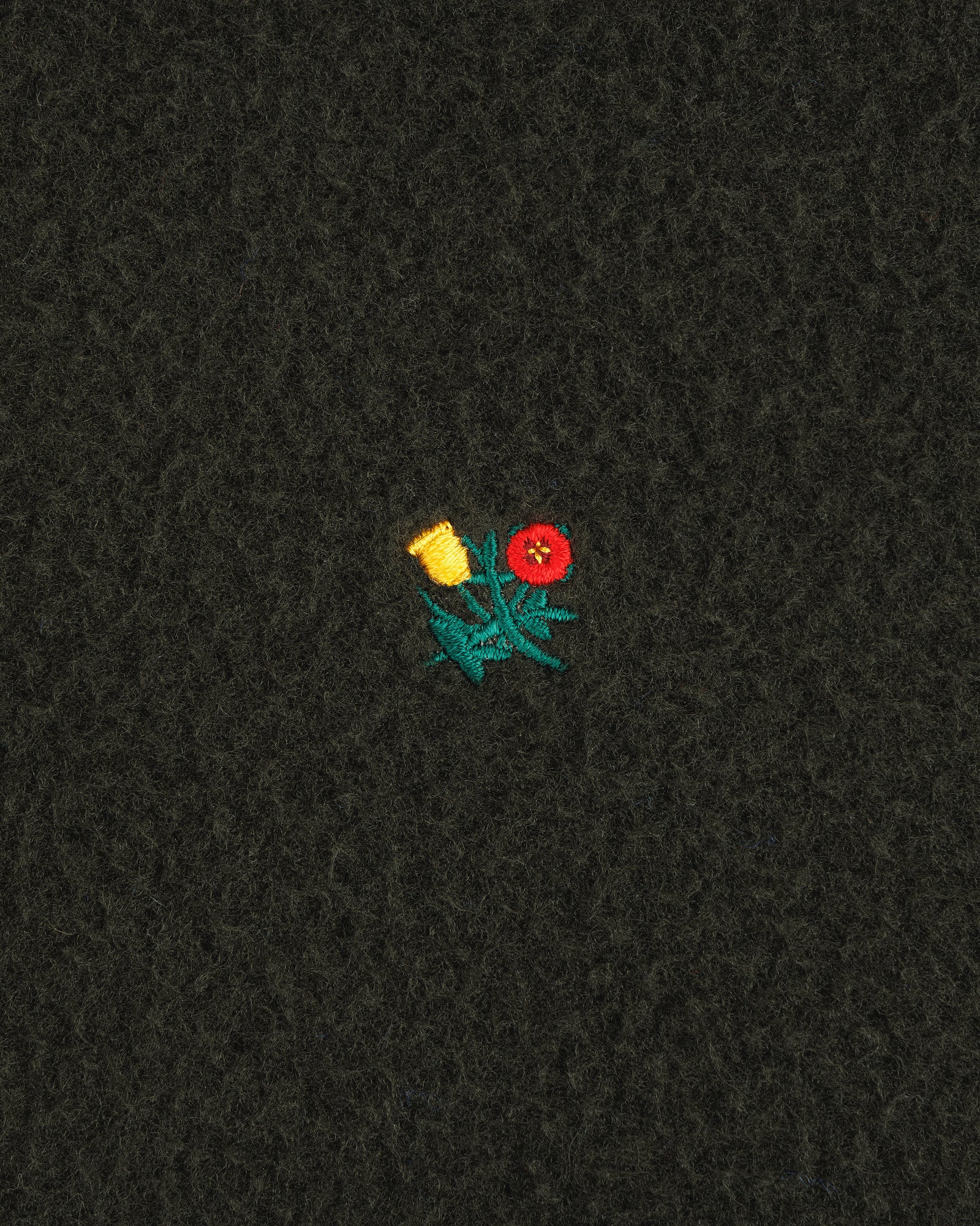 A small embroidered yellow and red flower with green leaves features on the Casentino Crest Half-Zip Pullover.