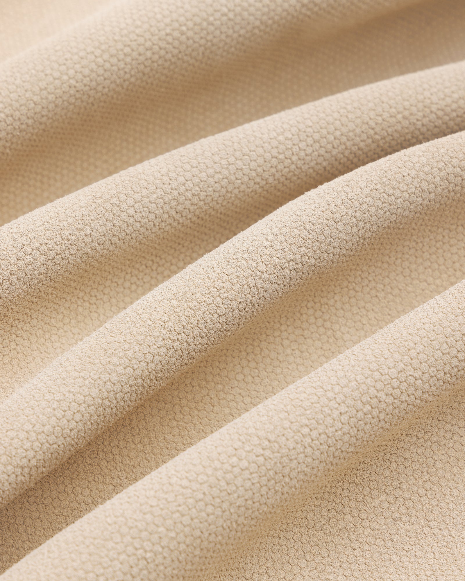 Close-up of beige textured Leather Ranch Jacket with small hexagonal patterns and soft, wavy folds.
