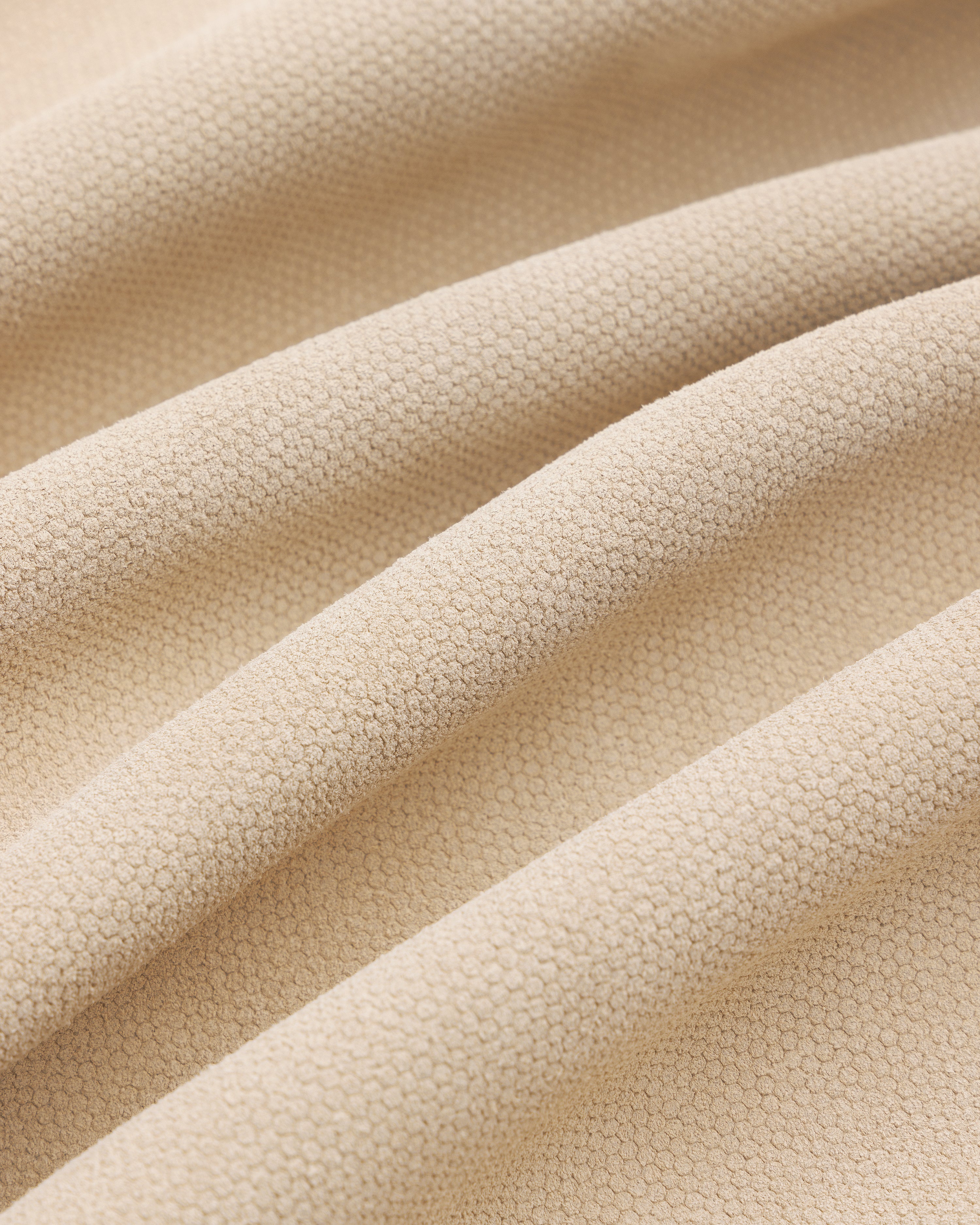 Close-up of beige textured Leather Ranch Jacket with small hexagonal patterns and soft, wavy folds.
