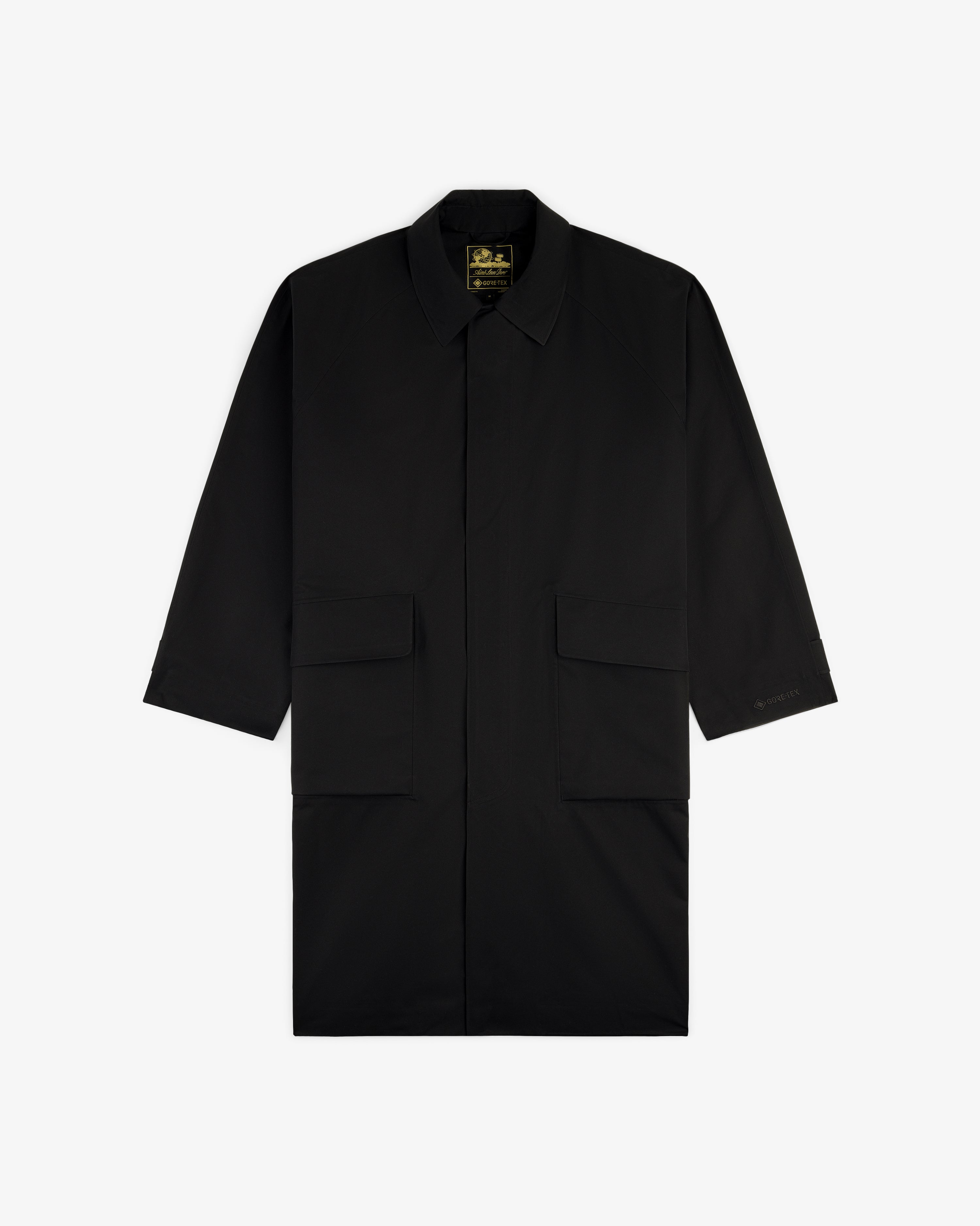 Black GORE-TEX Balmacaan Coat with long sleeves, collar, and two large front pockets, shown on a white background.