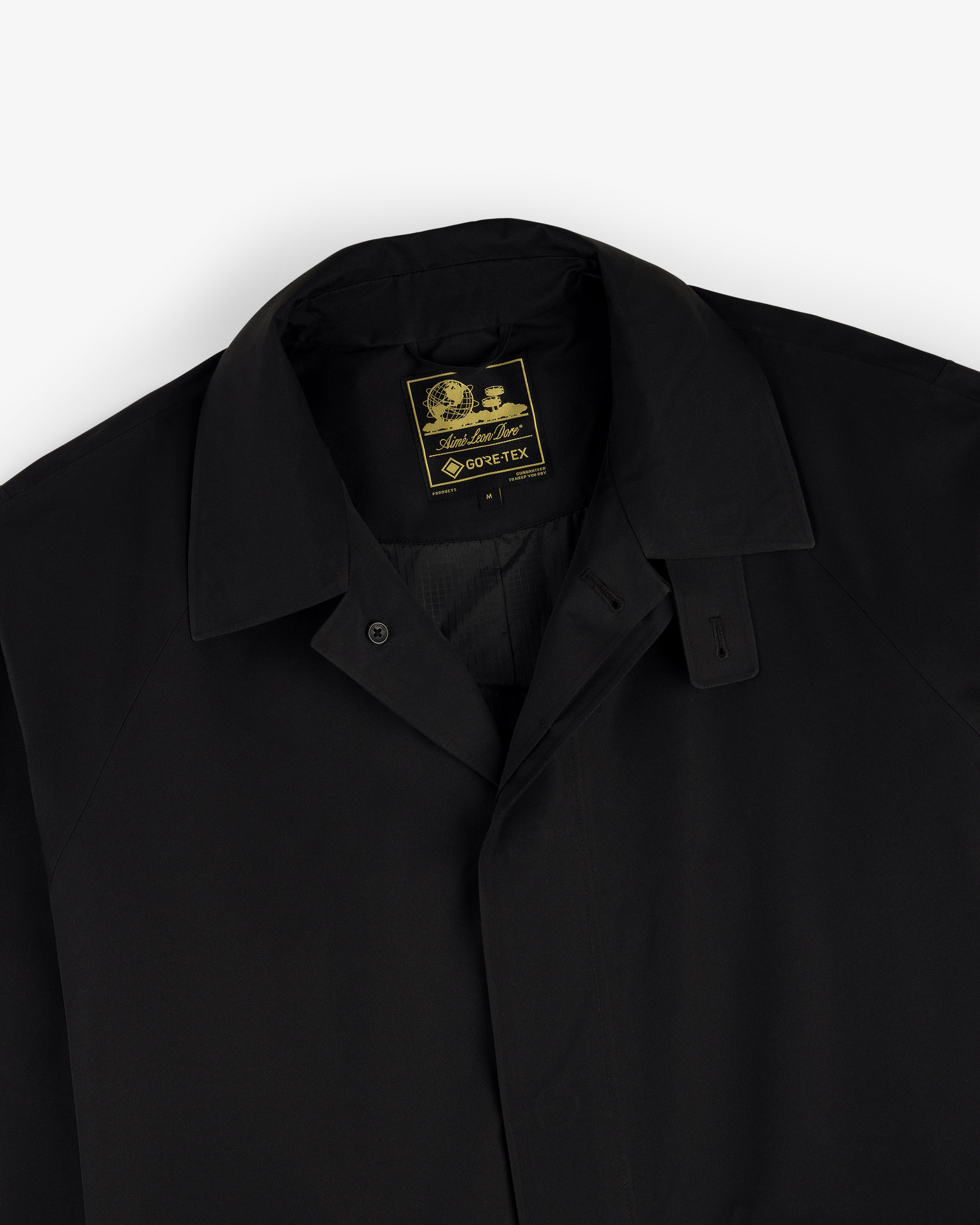 Black-collared GORE-TEX Balmacaan Coat with a visible yellow and black label on the inner neck.