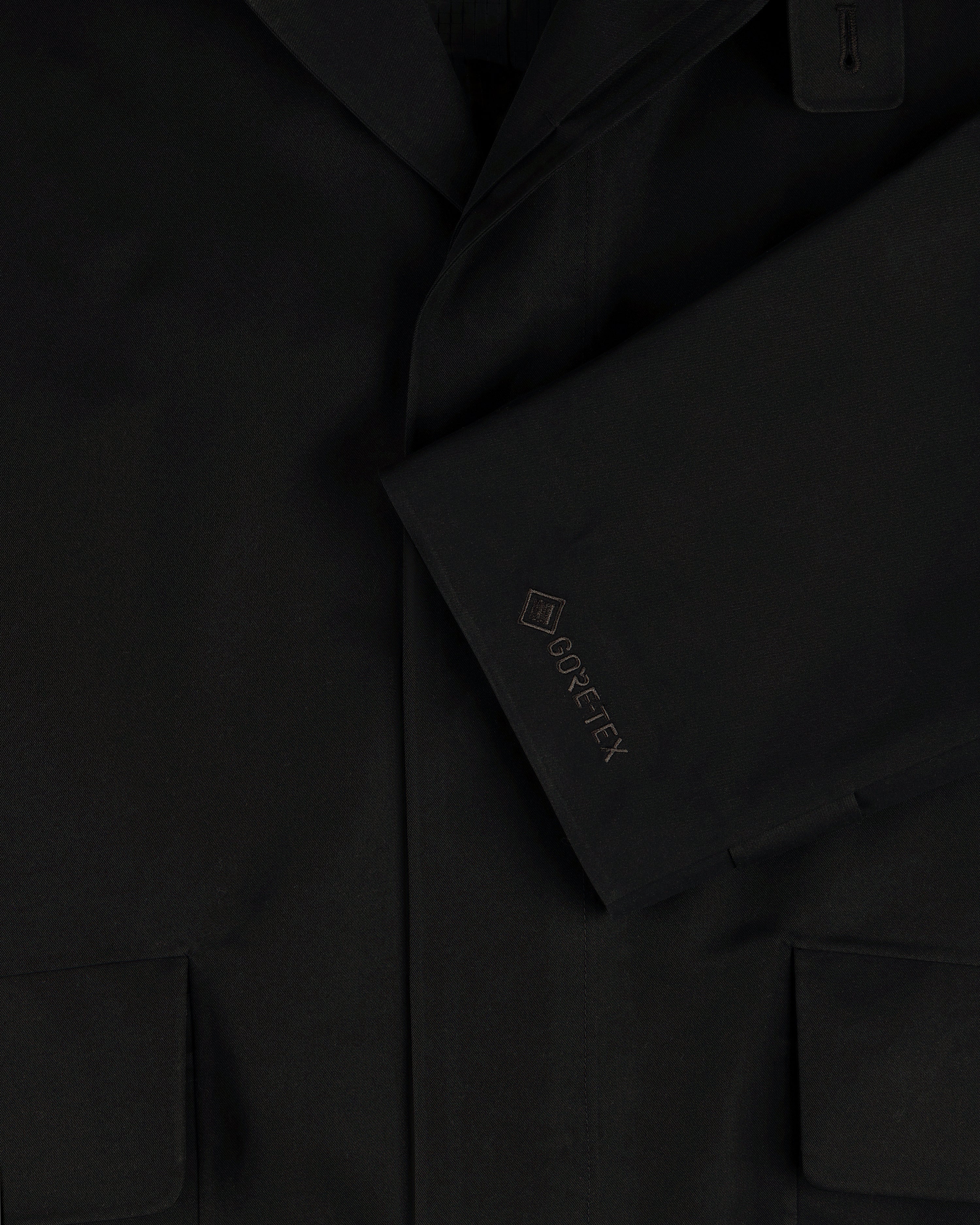 Close-up of the GORE-TEX Balmacaan Coat’s black sleeve with GORE-TEX embroidery and two front pockets.
