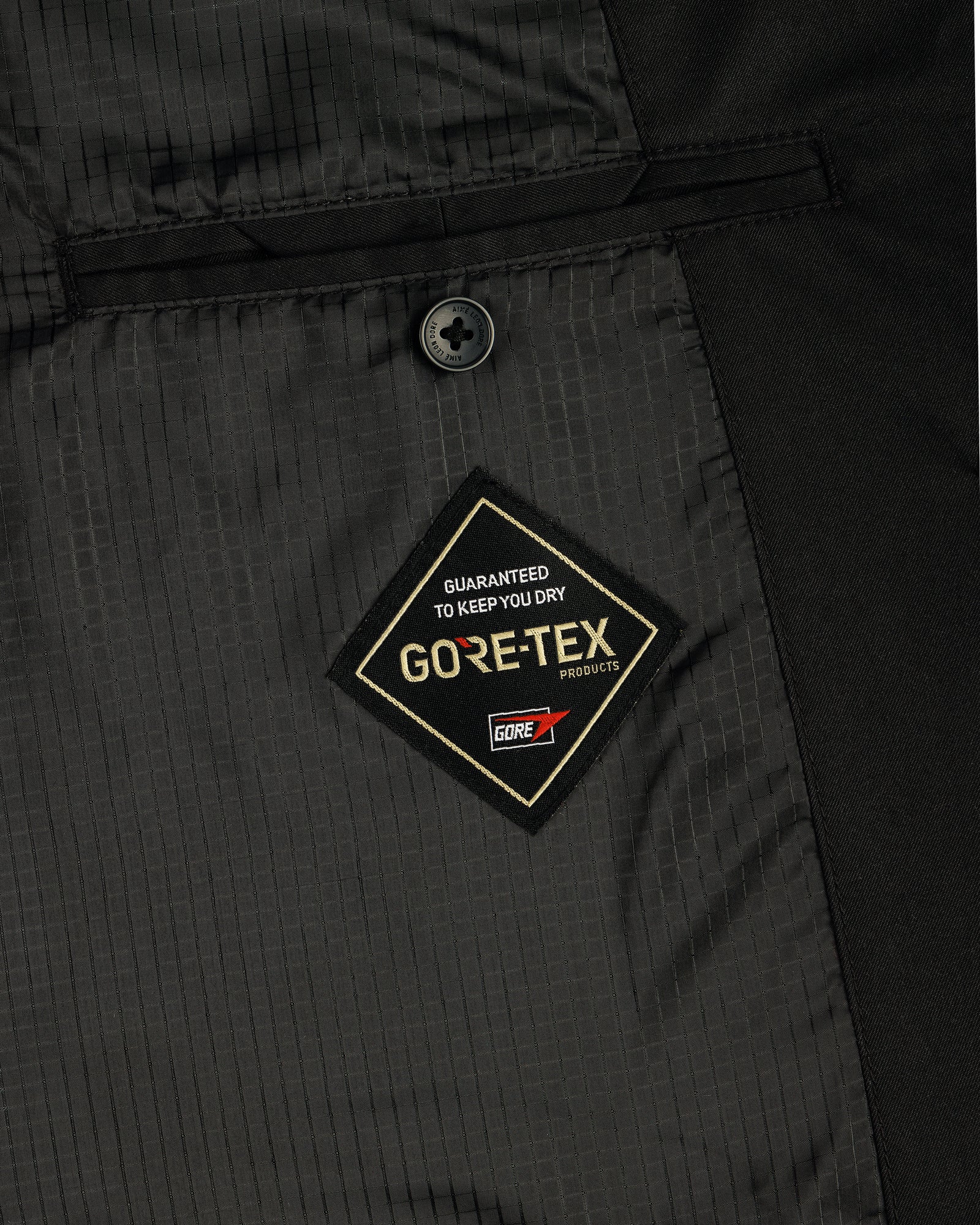 Close-up of the GORE-TEX Balmacaan Coat's black interior with a stitched GUARANTEED TO KEEP YOU DRY label.