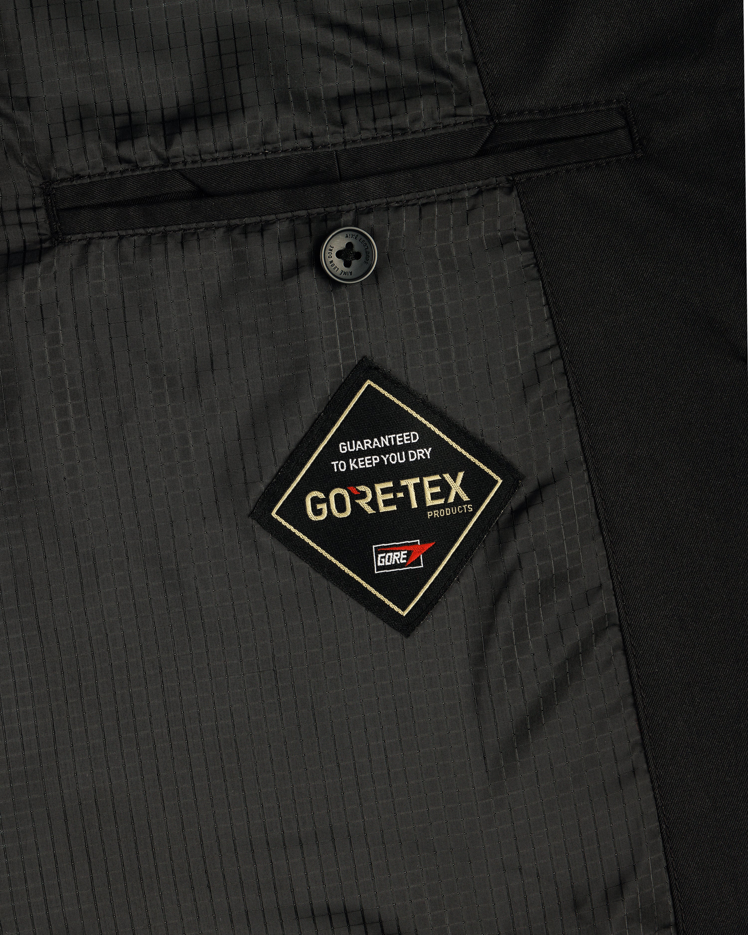 Close-up of the GORE-TEX Balmacaan Coat's black interior with a stitched GUARANTEED TO KEEP YOU DRY label.