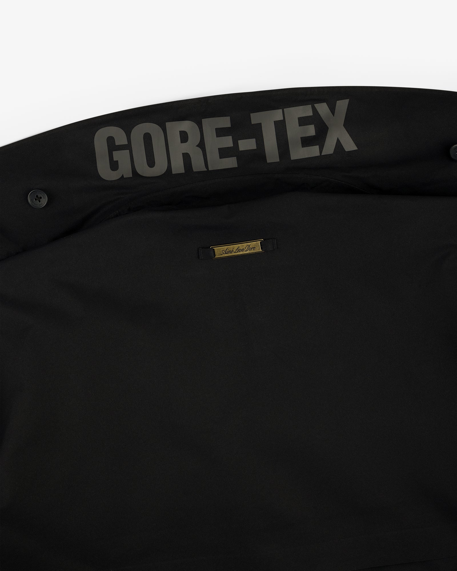 Close-up of GORE-TEX Balmacaan Coat's black collar with GORE-TEX text and a gold Social Status label.