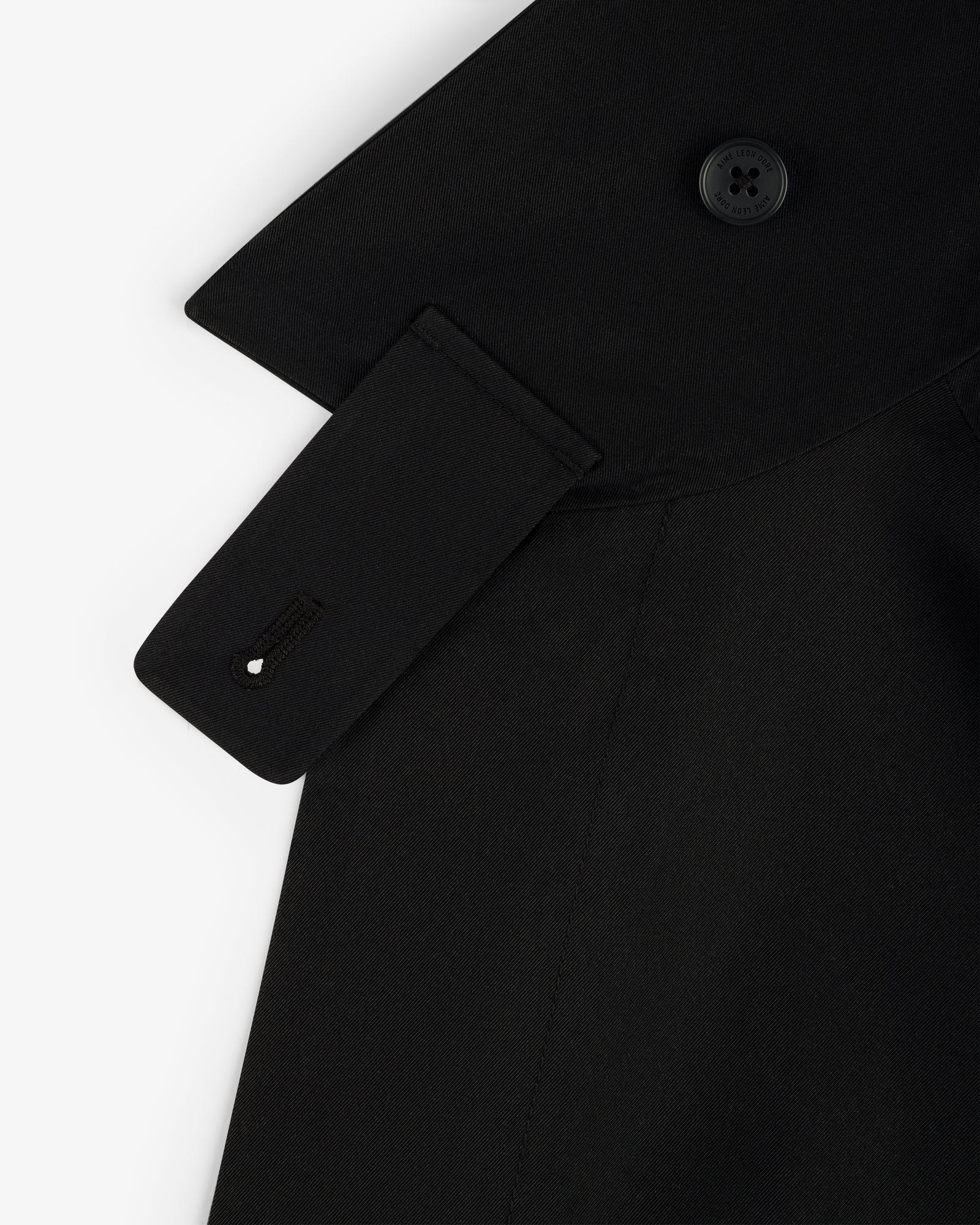 Close-up of the GORE-TEX Balmacaan Coat in black, showing the collar, button, and strap detail on white background.