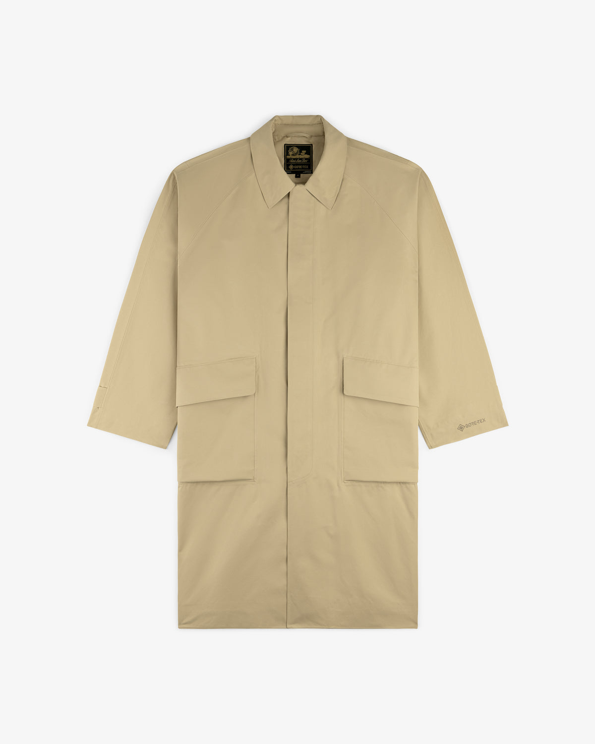 GORE-TEX Balmacaan Coat in beige, knee-length with collar and two large front pockets, laid flat on white background.