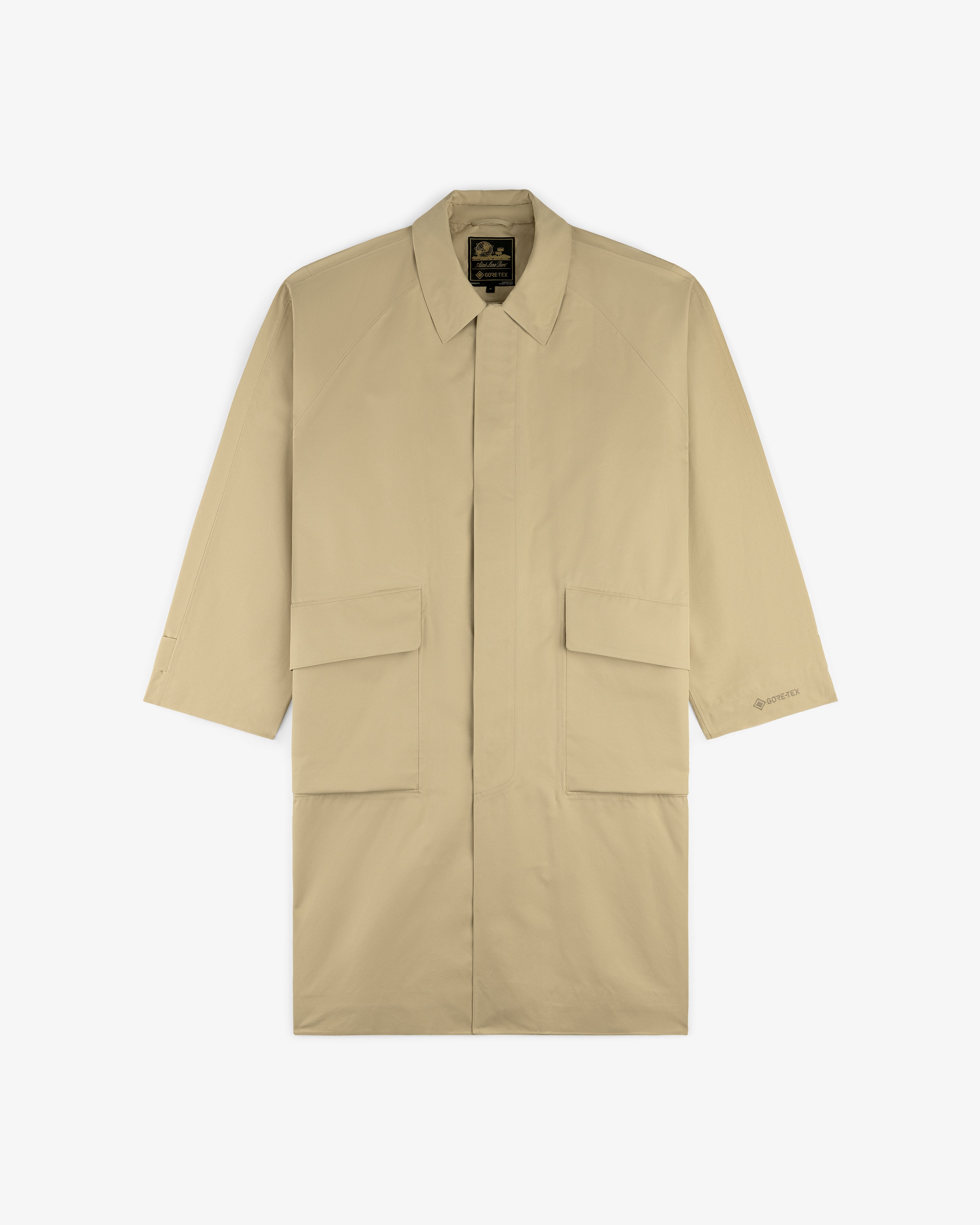 GORE-TEX Balmacaan Coat in beige, knee-length with collar and two large front pockets, laid flat on white background.