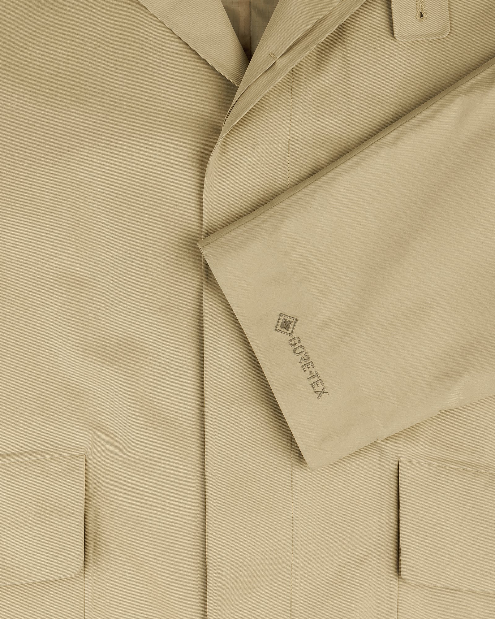 Close-up of the GORE-TEX Balmacaan Coat in beige, featuring large pockets and GORE-TEX embroidered on the sleeve.