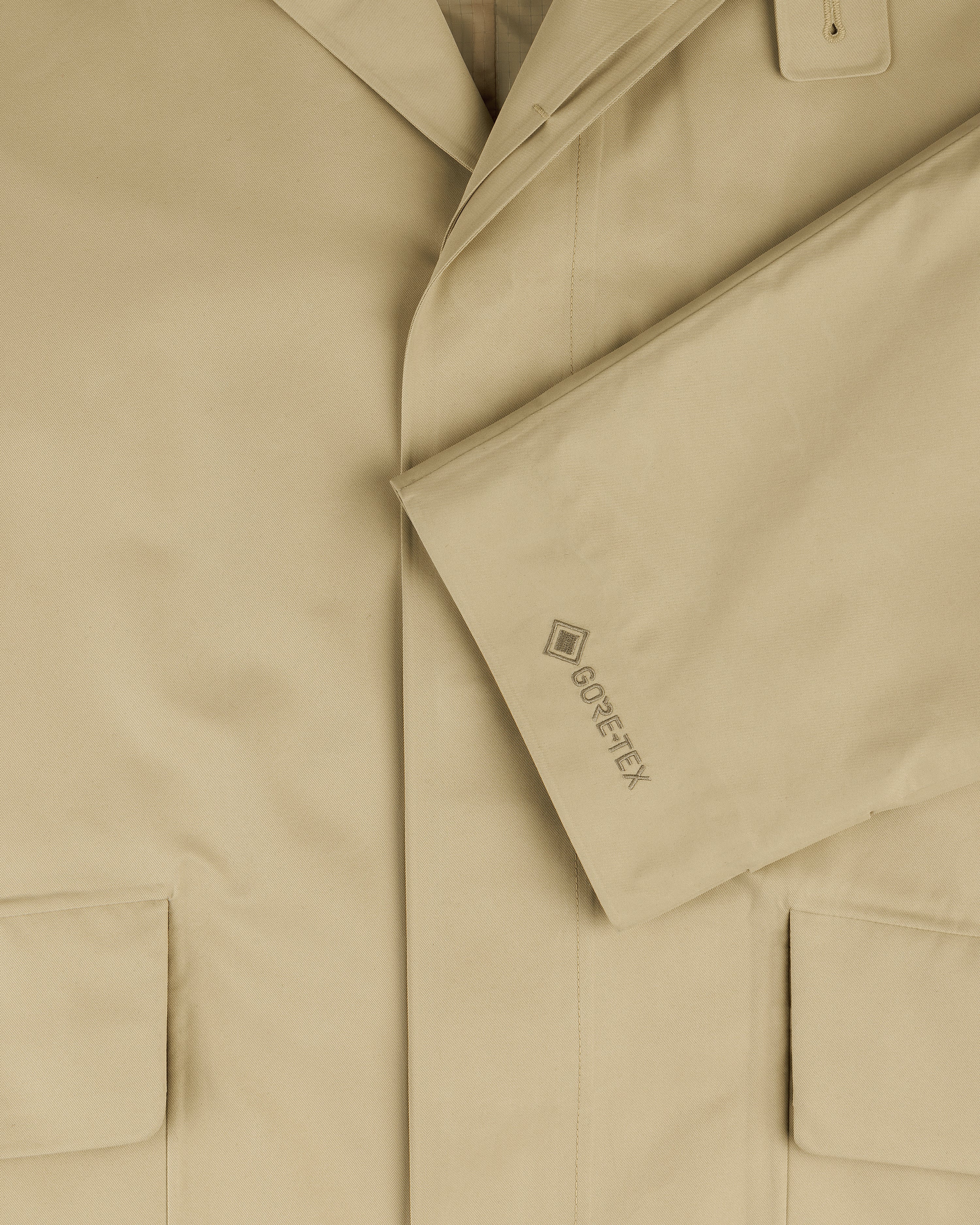 Close-up of the GORE-TEX Balmacaan Coat in beige, featuring large pockets and GORE-TEX embroidered on the sleeve.