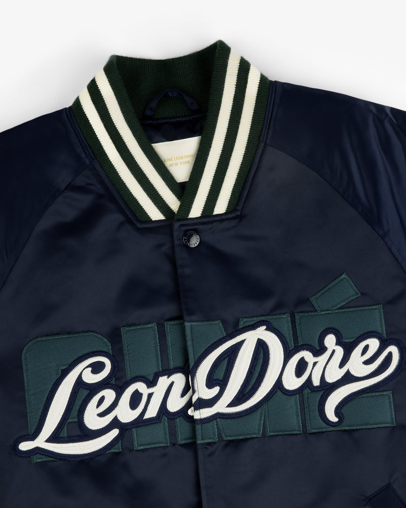 Overlay Logo Satin Varsity Jacket in navy with striped collar and green and white embroidered Leon Dore chest logo.